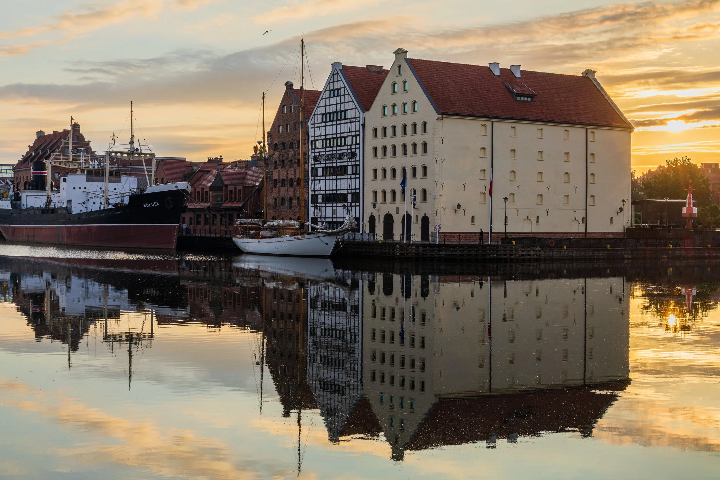 Reflections of historic buildings in the water along the Motława River in Gdańsk.
