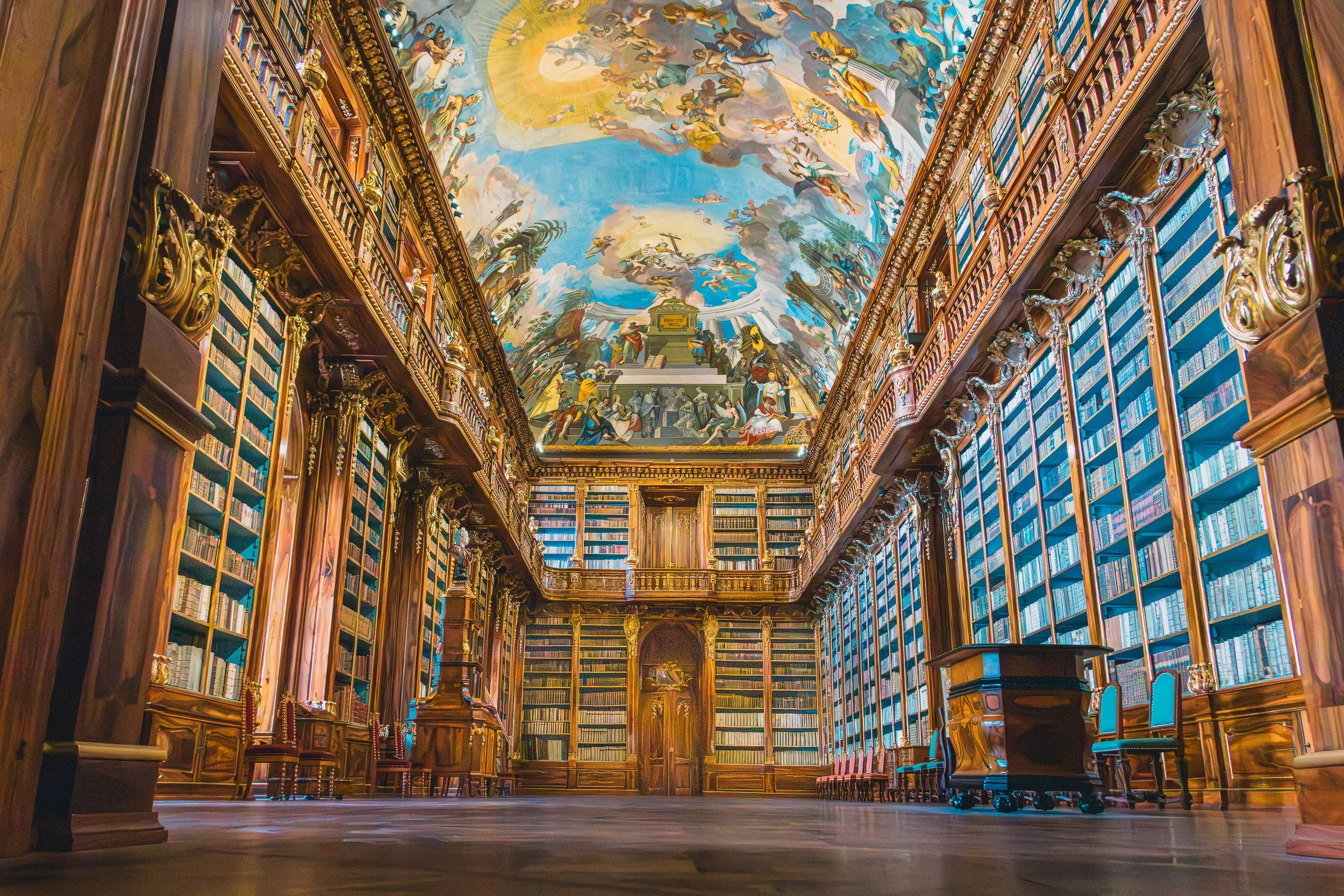 Ornate historic library in Prague with floor-to-ceiling bookshelves and a painted ceiling