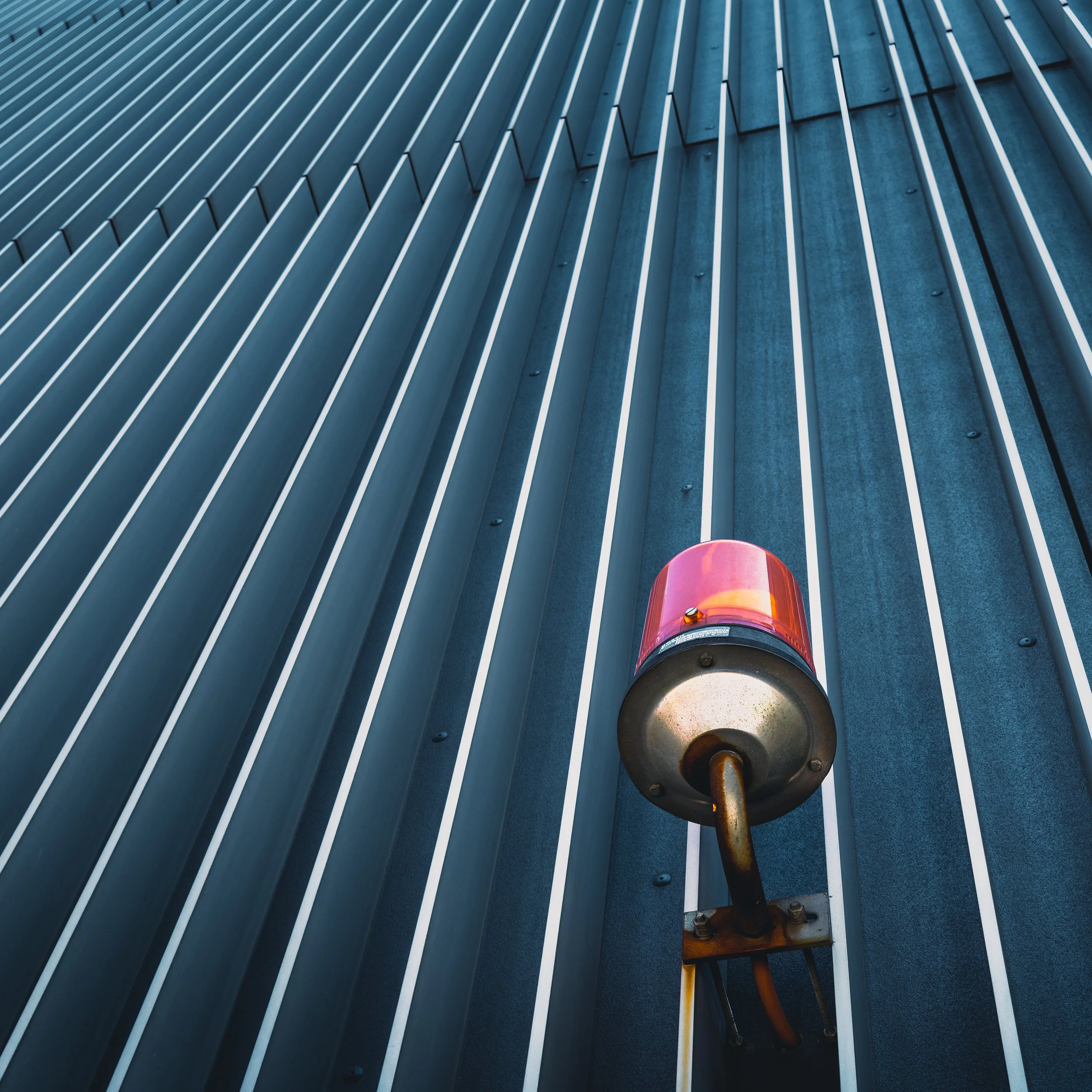 Red warning light set against vertical lines of a modern high-rise facade