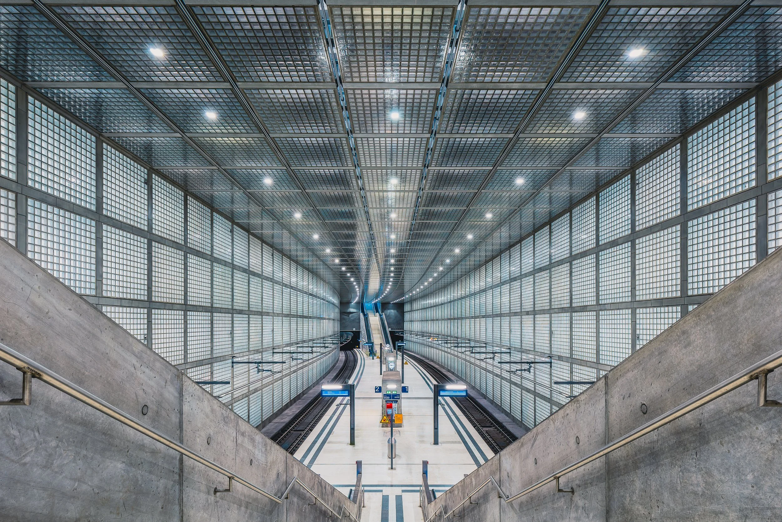 Symmetrical modern train station with escalators and repeating architectural lines