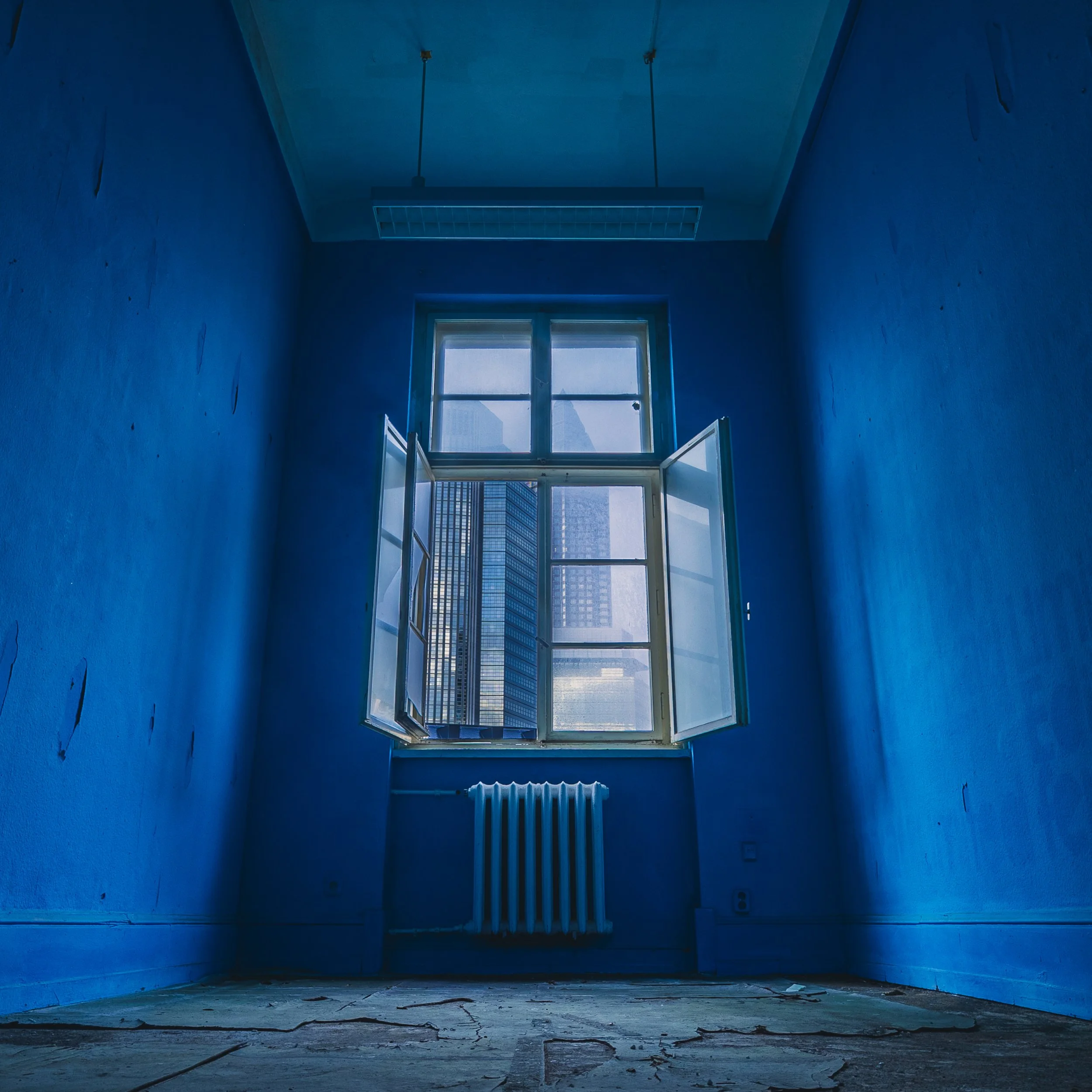 Blue architectural interior with a single window and radiator
