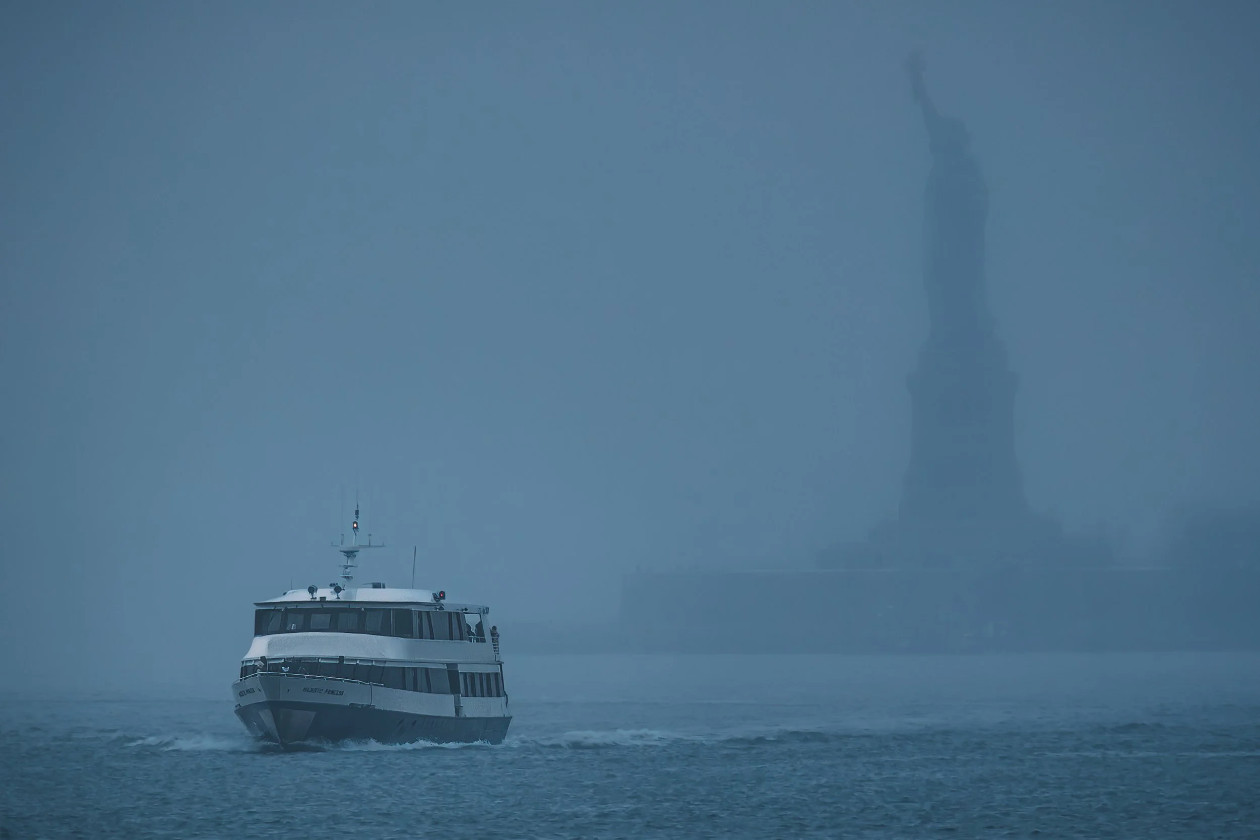 Ship emerging from dense fog with the Statue of Liberty fading in the background
