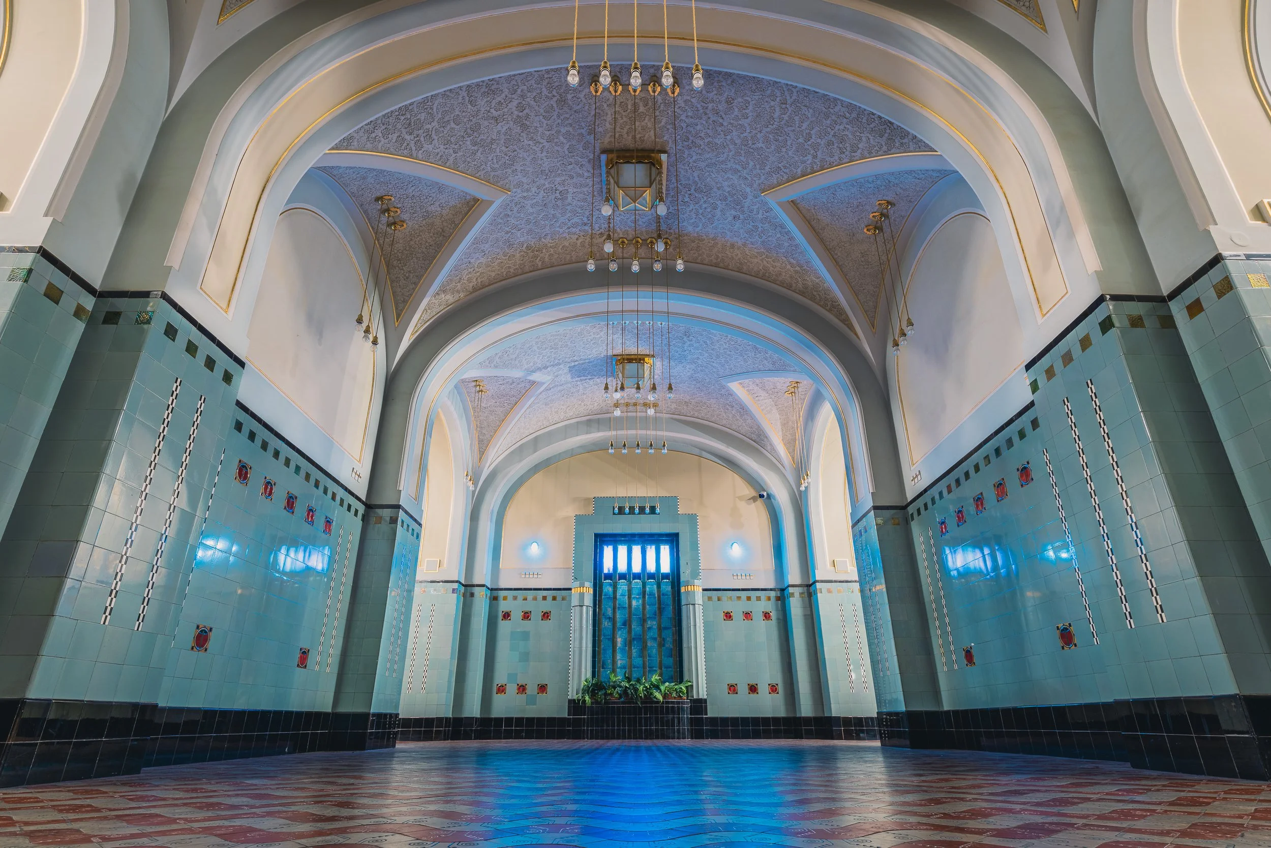 Symmetrical cellar hall in Prague's Municipal House with arched ceilings and blue-green tiled walls