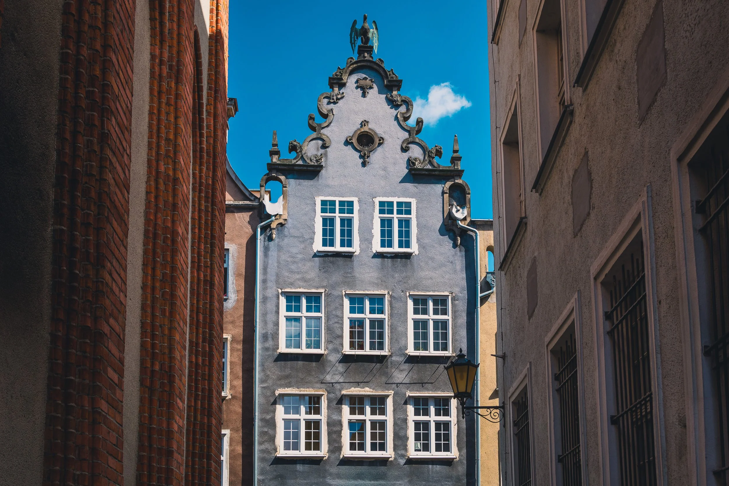 Historic house framed through a narrow gap between buildings in Gdańsk
