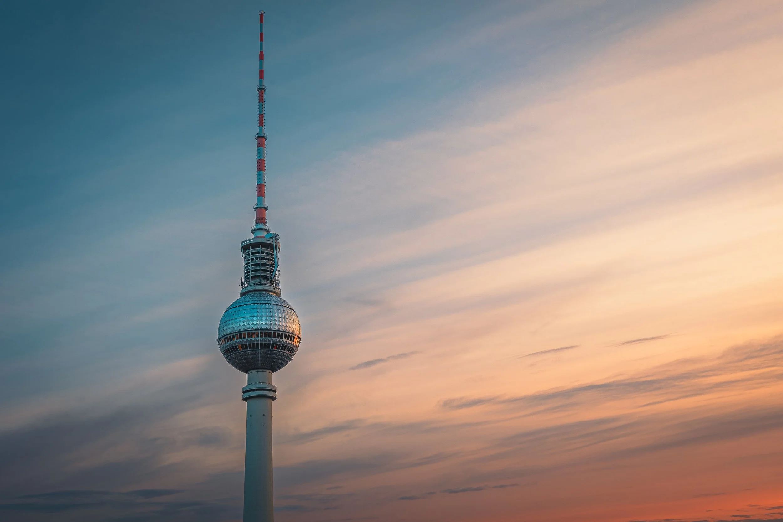 Berlin TV Tower against a softly streaked sunset sky