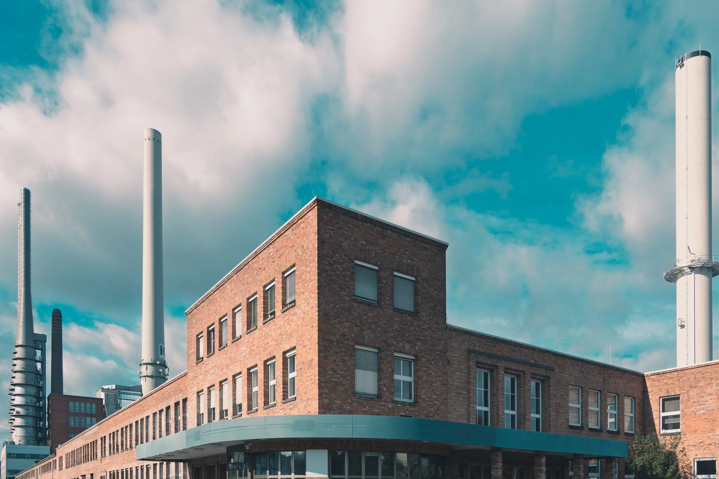 Historic brick factory building and industrial chimneys in Miltenberg beneath a blue sky