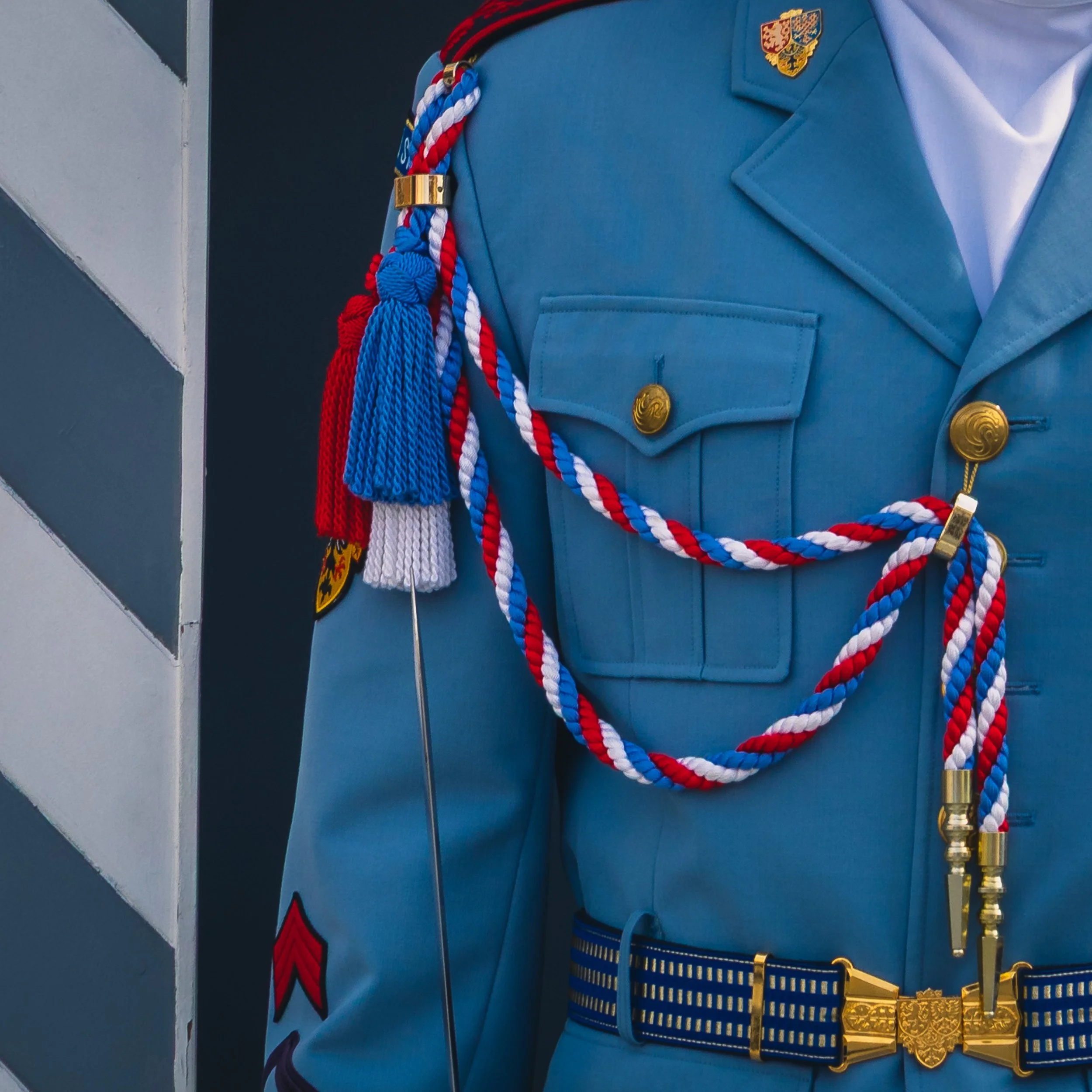 Close-up of a blue ceremonial guard uniform with red, white and blue cords in Prague