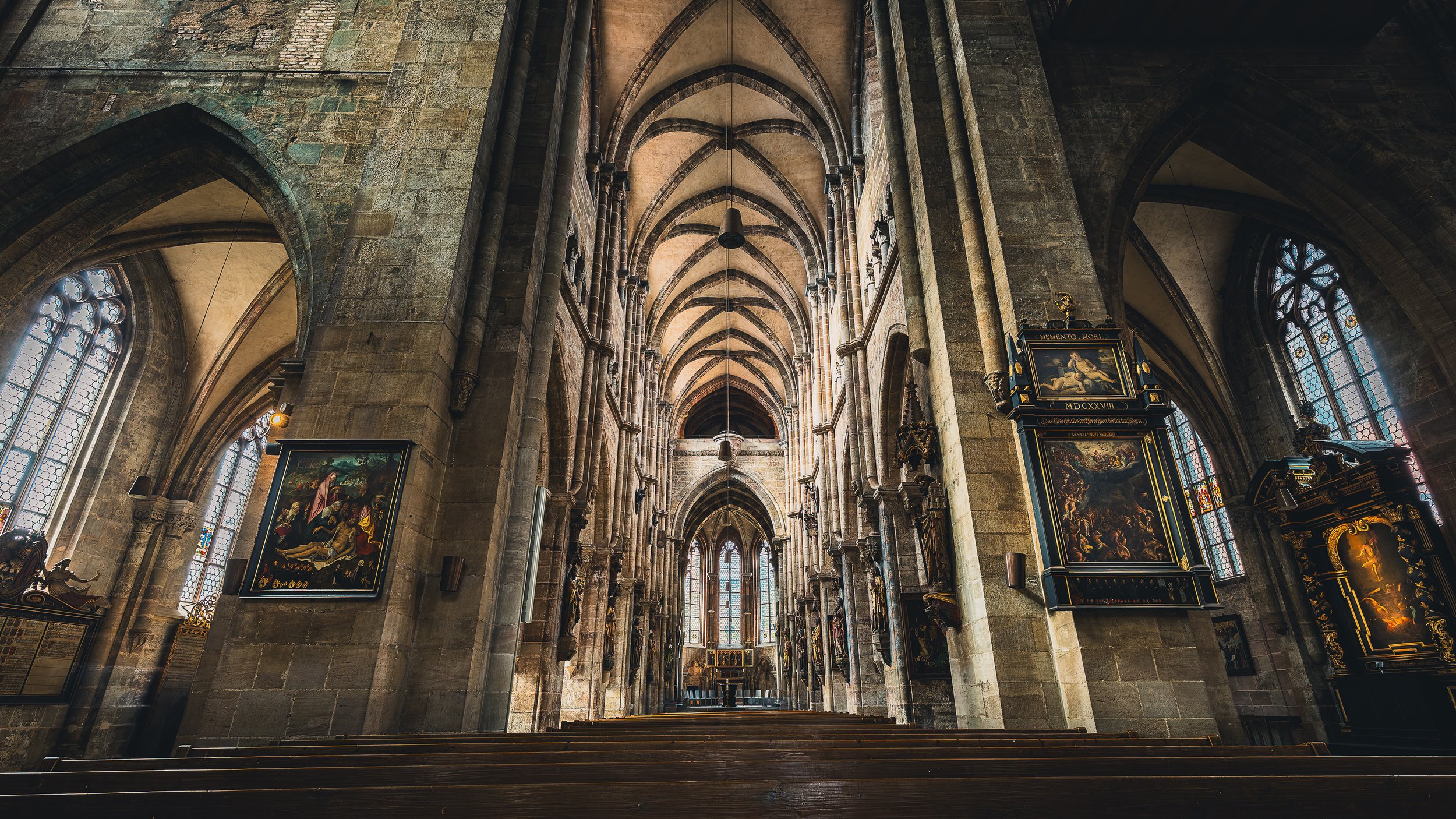 Long Gothic nave inside St. Sebald Church in Nuremberg with pointed arches and side paintings