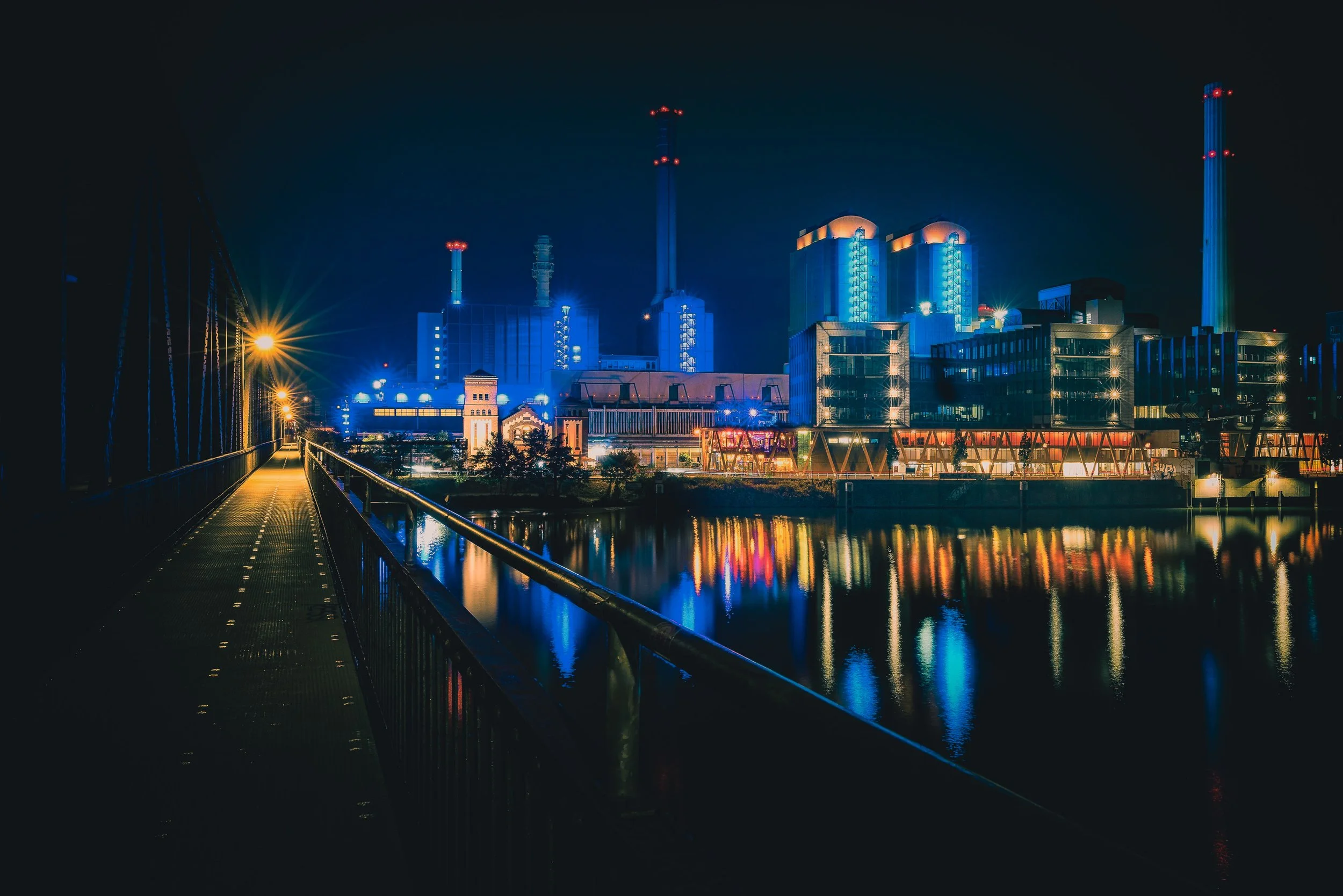 Heizkraftwerk West in Frankfurt illuminated at blue hour and reflected in the Main River
