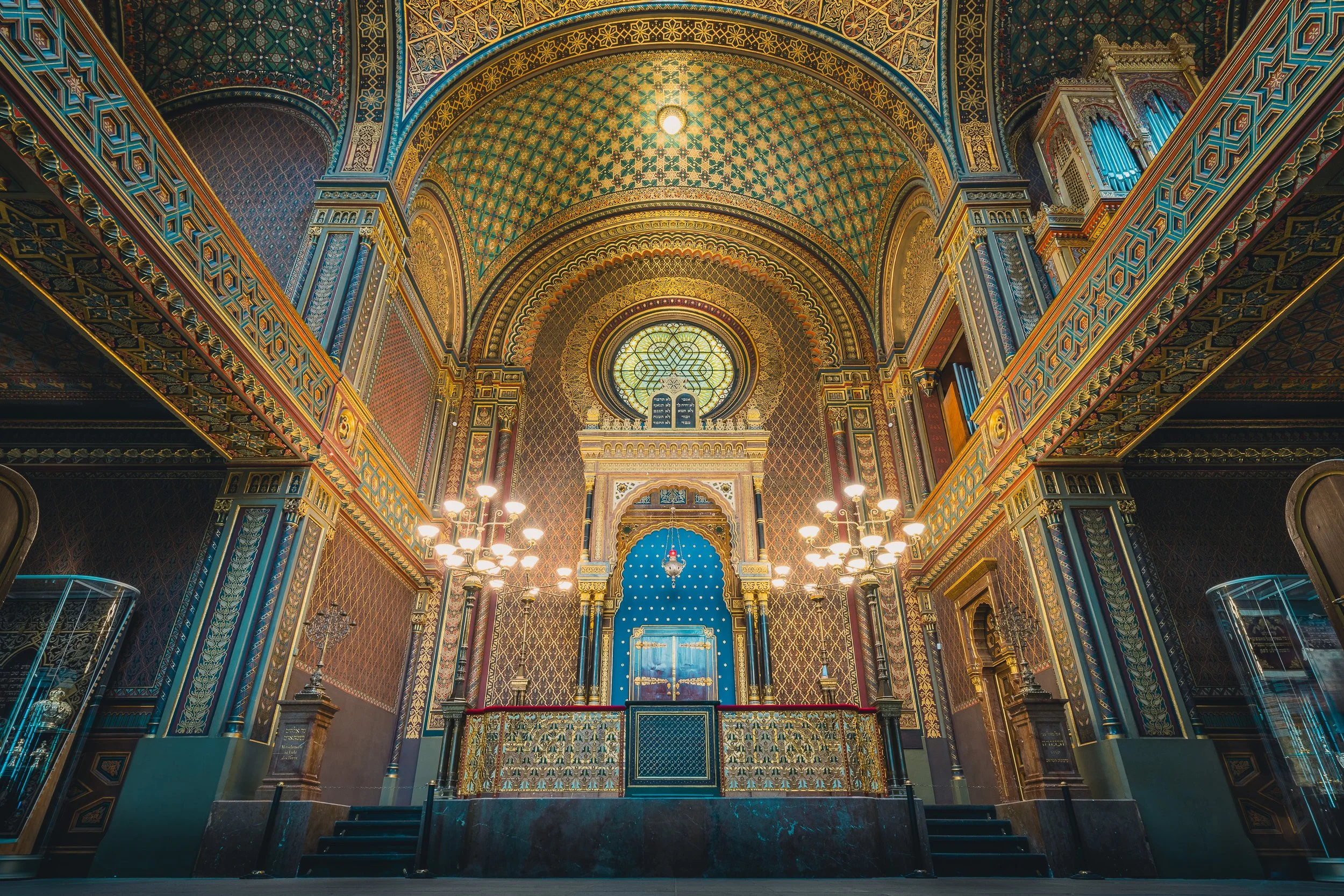 Ornate interior of the Spanish Synagogue in Prague with patterned arches and chandeliers