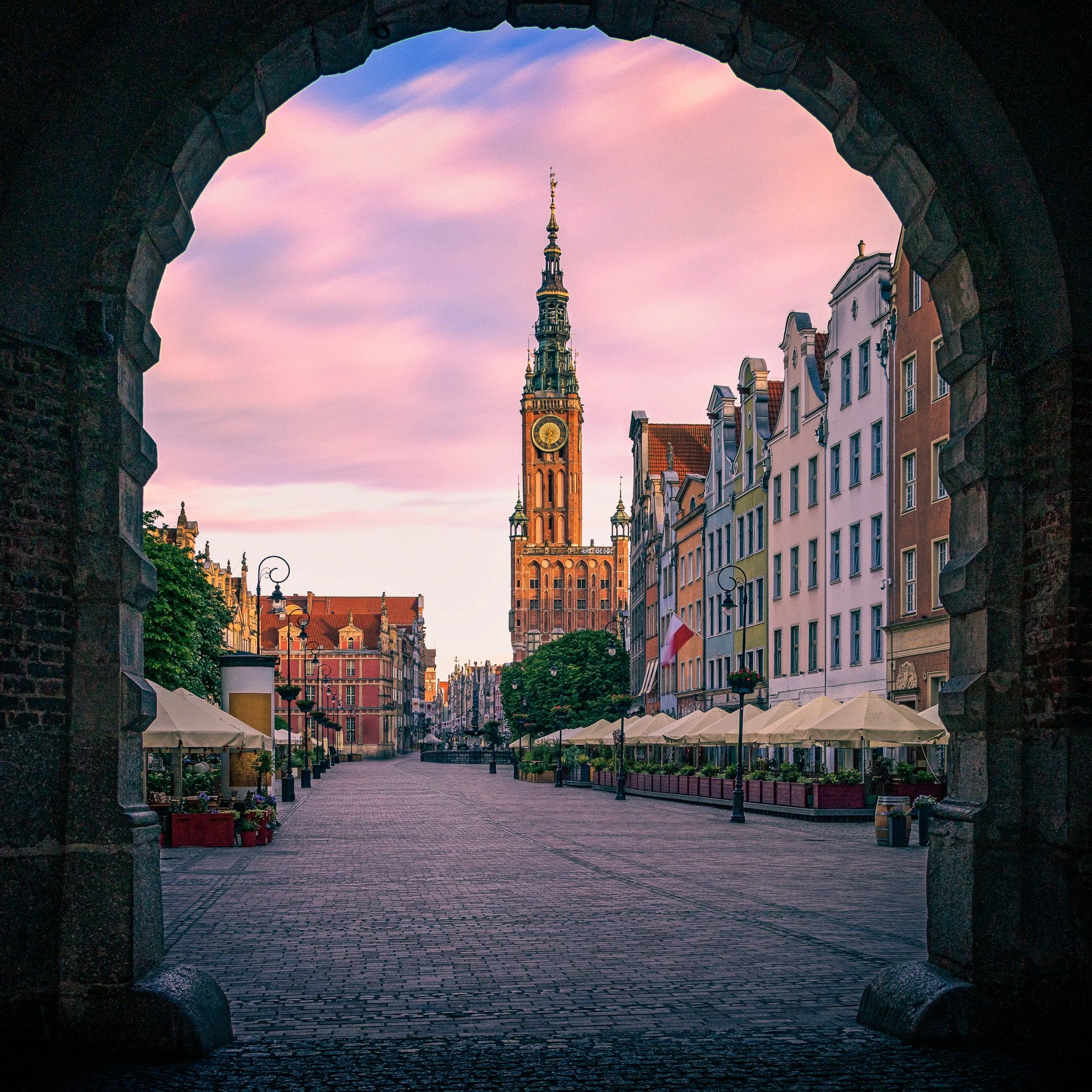 A view through a historic arch towards the buildings of Gdańsk.