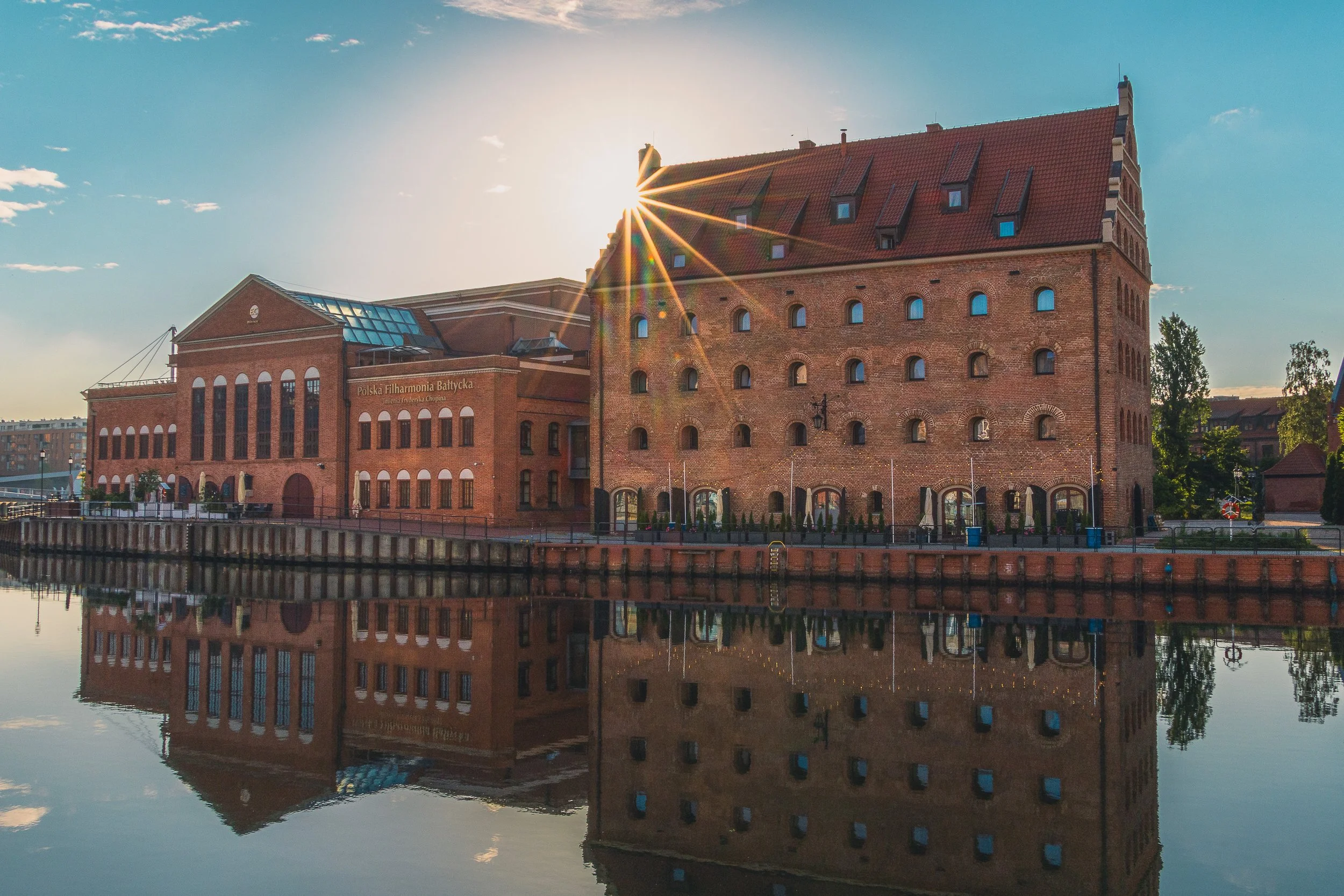 Historic waterfront buildings reflected in calm water in Gdańsk