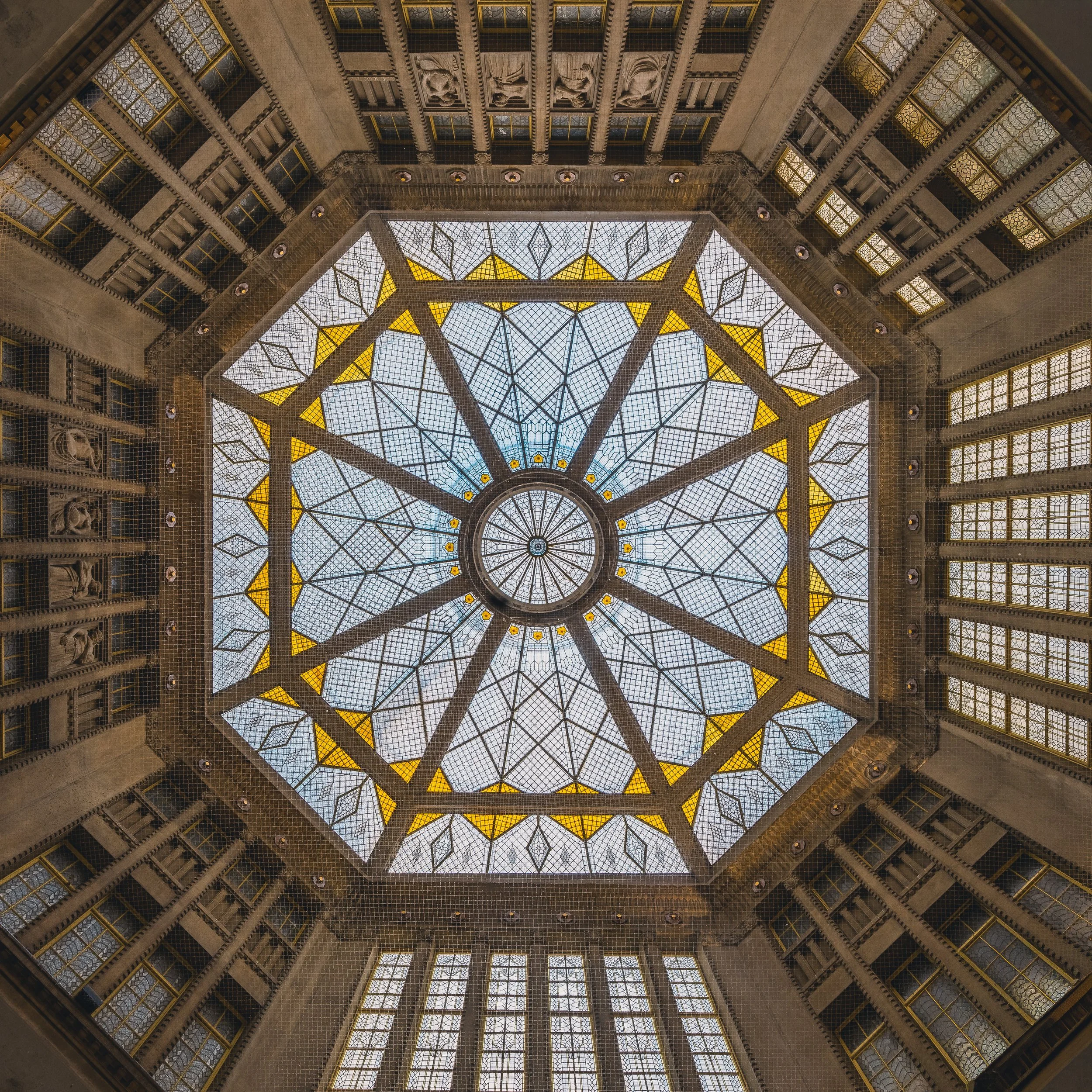 Geometric stained-glass dome viewed directly from below in Prague