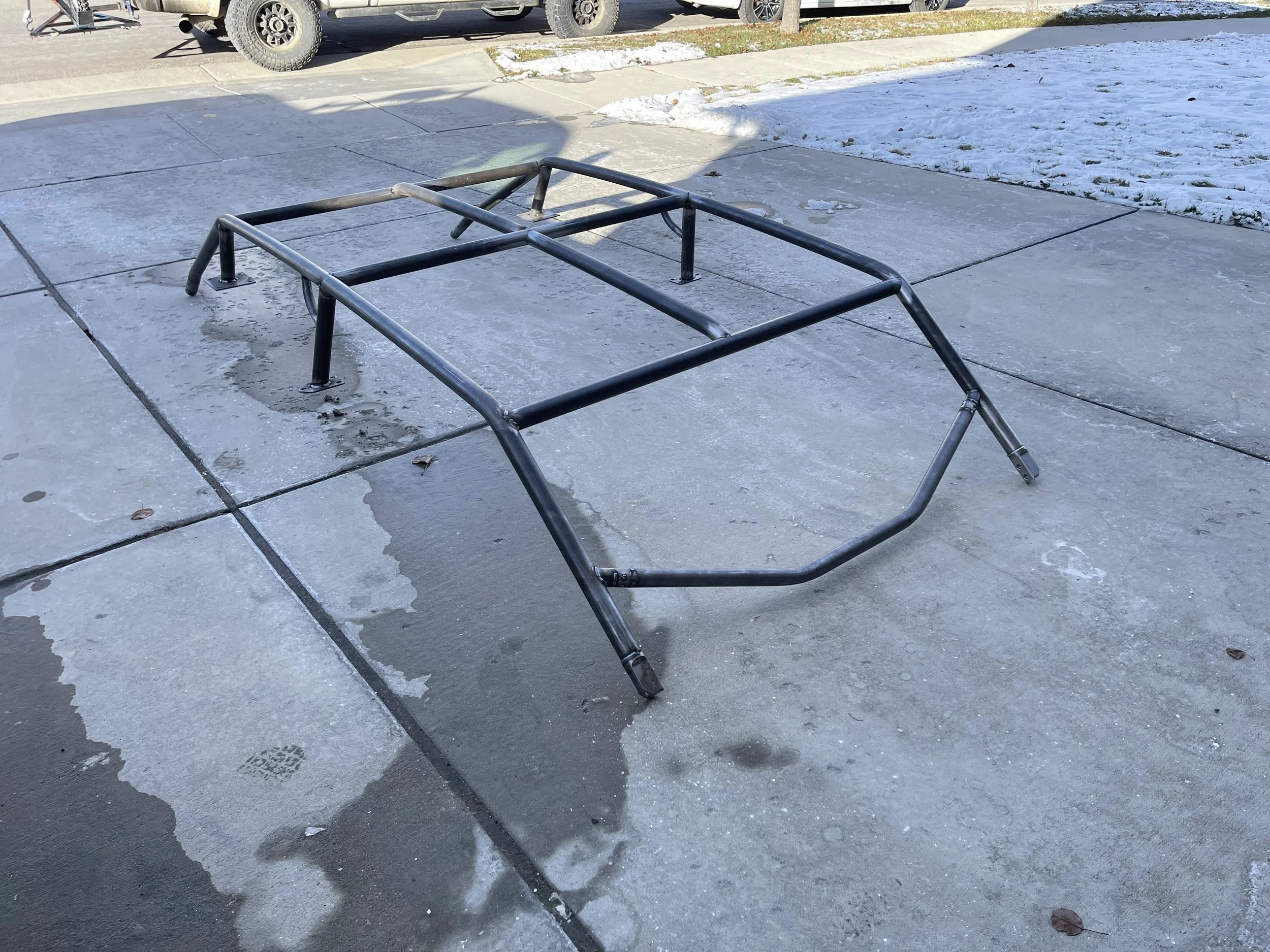 Custom steel side-by-side roll cage on a concrete driveway