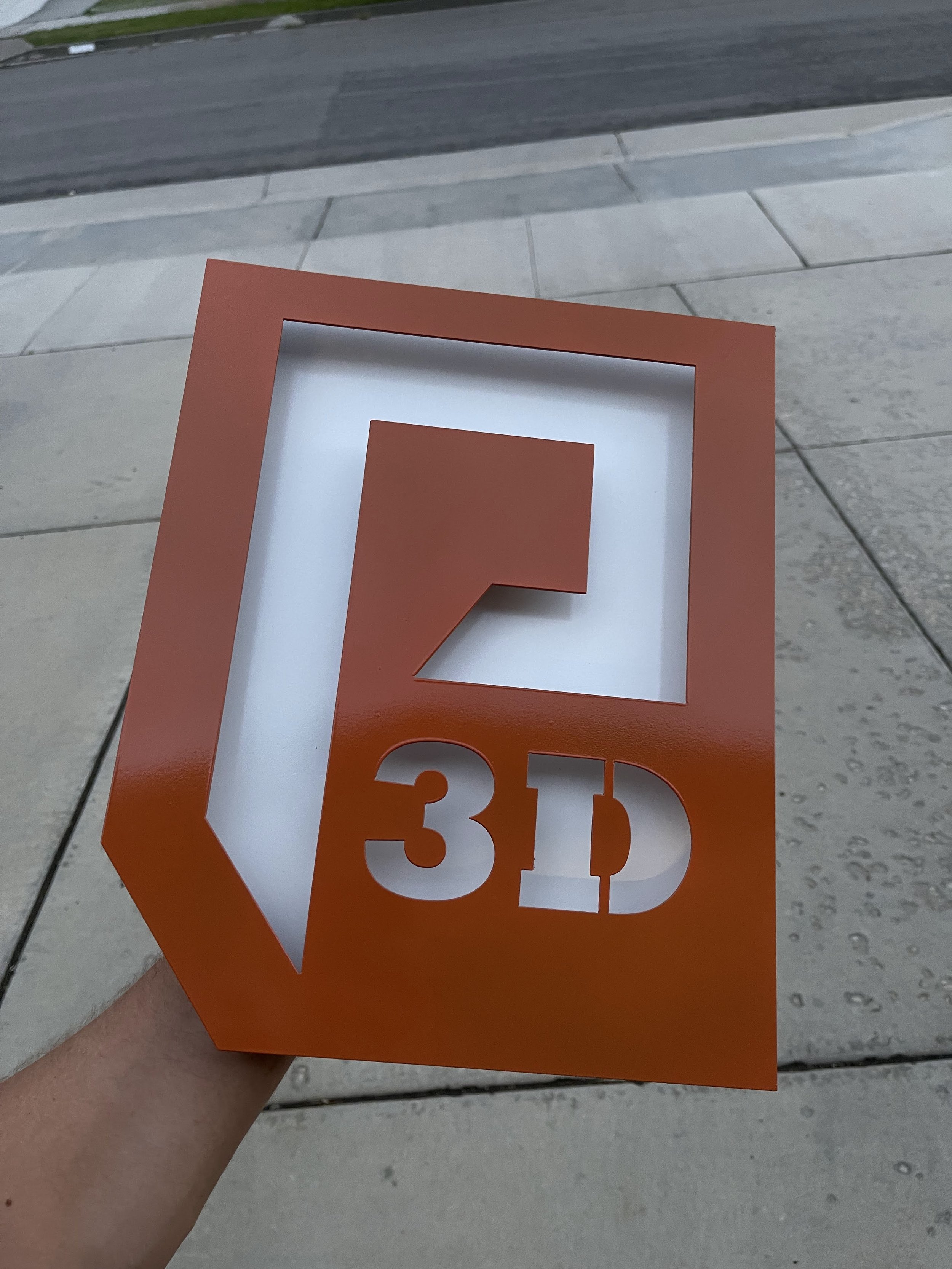 Plasma cut "P" sign with an orange powder coat and white backing