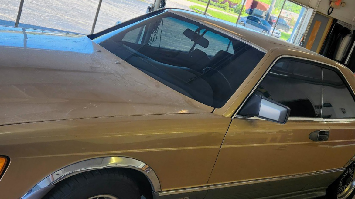 A gold-colored vintage coupe car parked inside a garage.