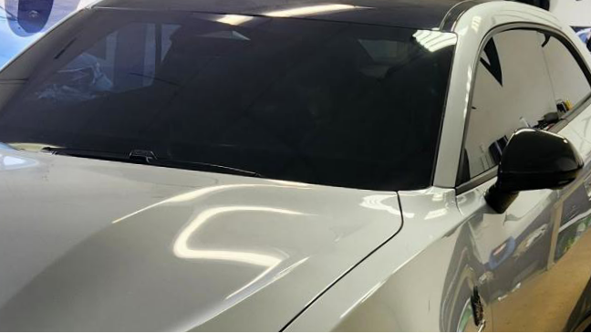A white car with tinted windows and black side mirrors.