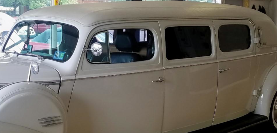 Vintage cream-colored car with black interior parked indoors.