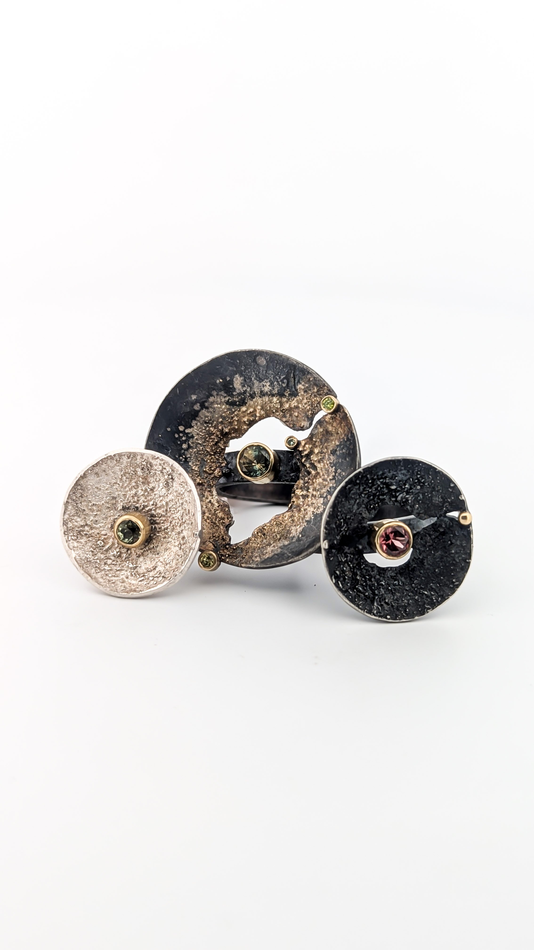 Three circular custom rings with embedded gemstones: sapphire, garnet, diamonds. Designs by Rocky Pardo Jewelry.