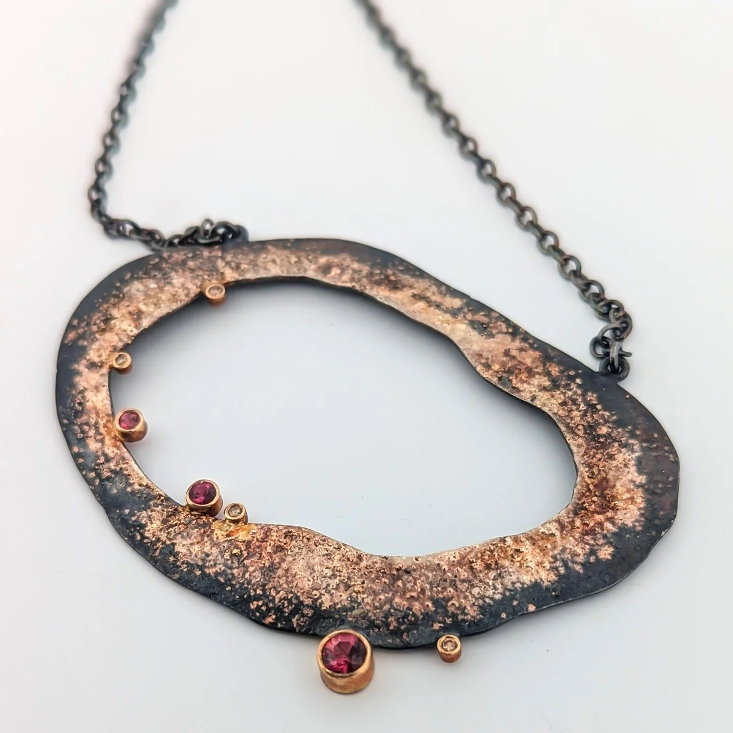 "Fire Geode" Necklace by Rocky Pardo⁠ ❤️&zwj;🔥✨️⁠
⁠
Oxidized sterling silver, 18k yellow gold dust, berry sapphire and champagne diamonds