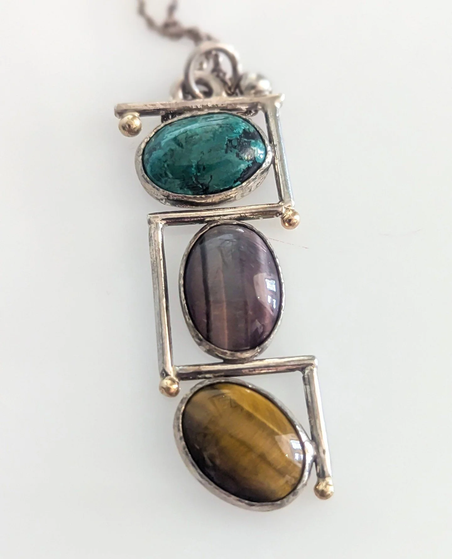 Triple stone pendant by Crazy Hair Designs by Susan Wismar ⁠💚💜🤎⁠
⁠
Sterling Silver, 14k Yellow Gold, Turquoise, Dyed Tiger Eye, Tiger Eye