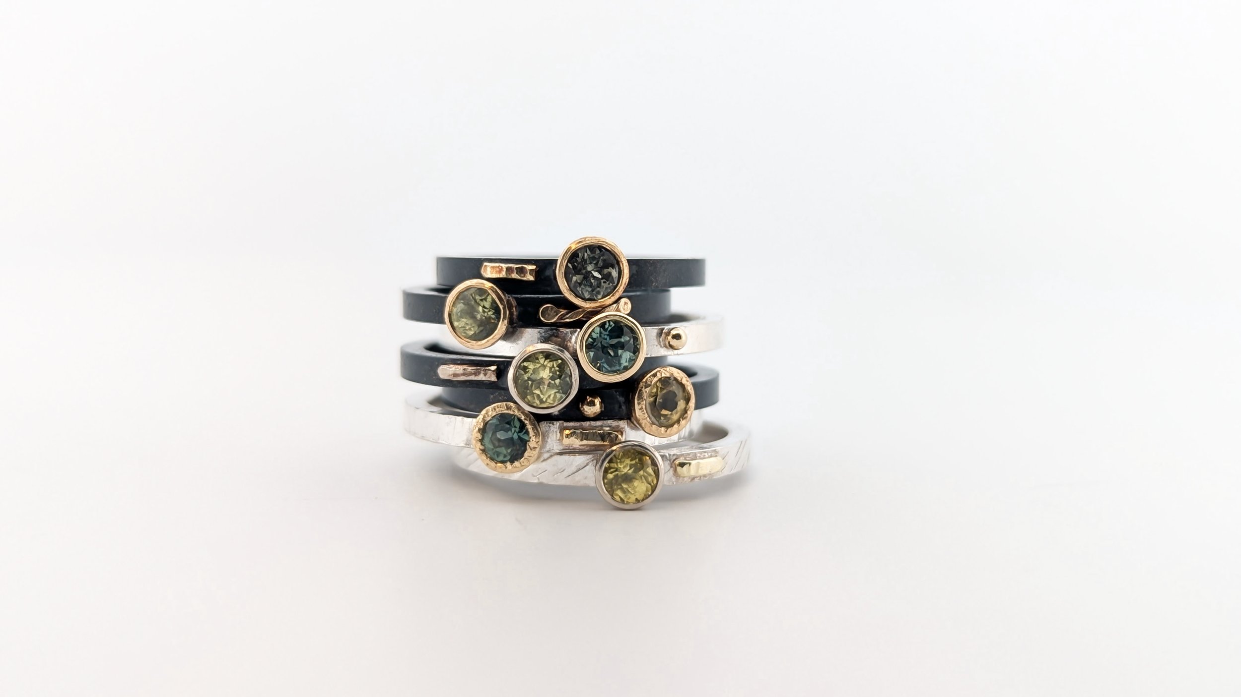 Stacked rings with various colored sapphire stones on a white background. Sola gemstone stackers by Rocky Pardo Jewelry.