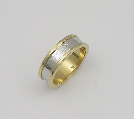 Gold and silver wedding band with a textured center and smooth edges.
