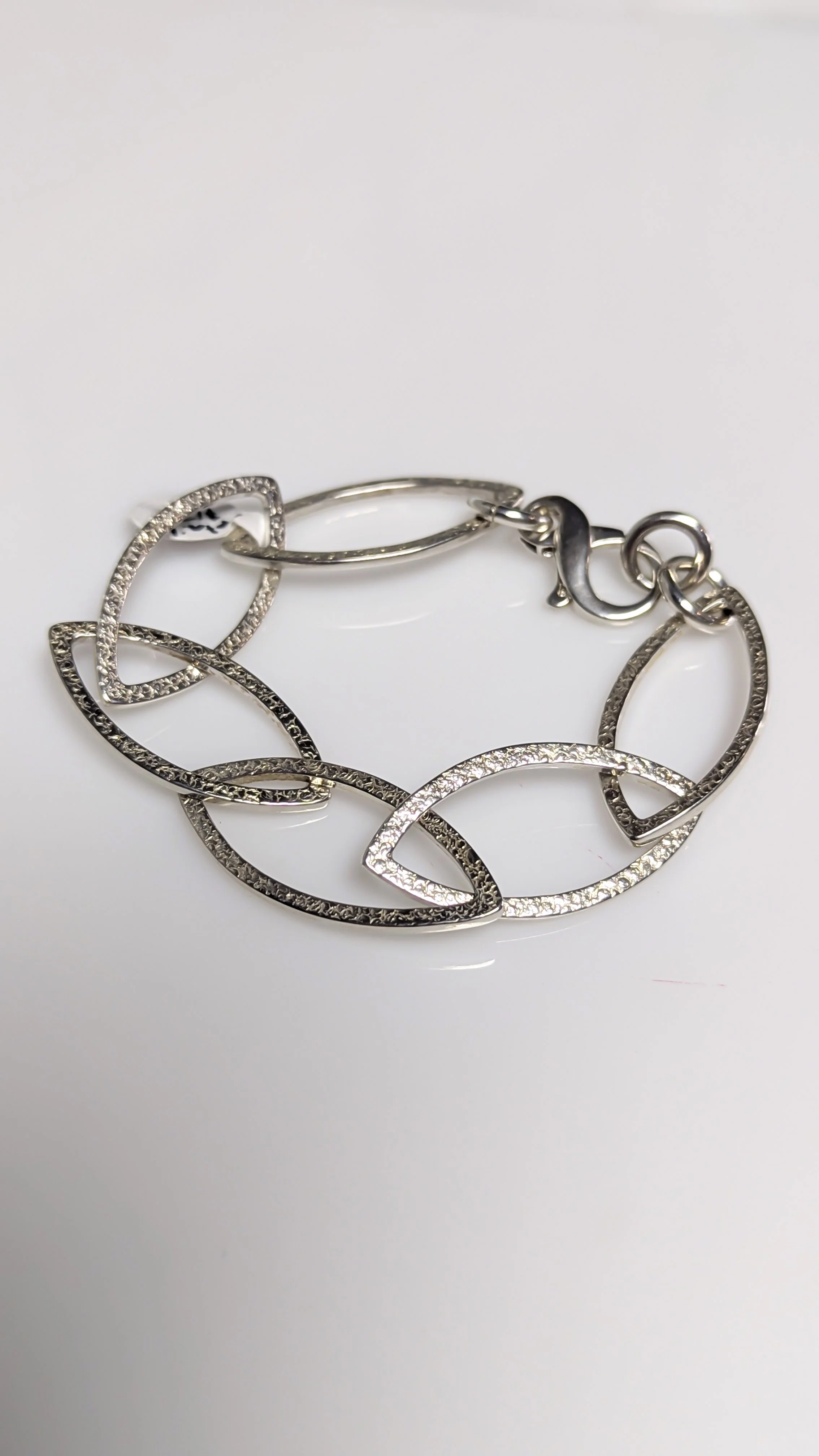 Silver bracelet with large oval-shaped links with texture. Design by David Luck.