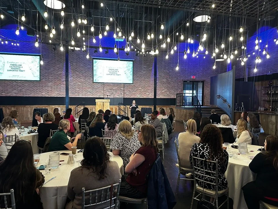Women in leadership members listening to member speak on stage at luncheon monthly gathering