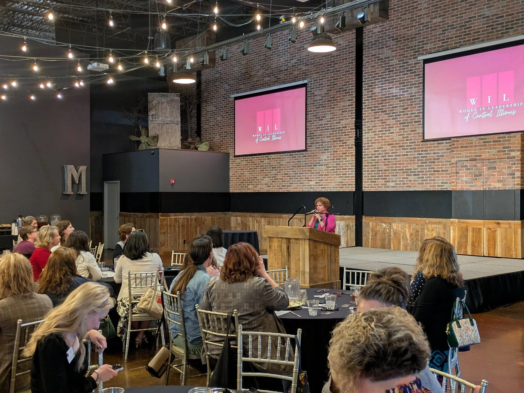 Women in leadership member speaking at a monthly luncheon event.