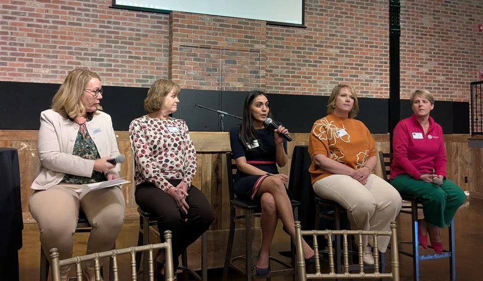 Women in leadership member speaking on stage at monthly luncheon event.