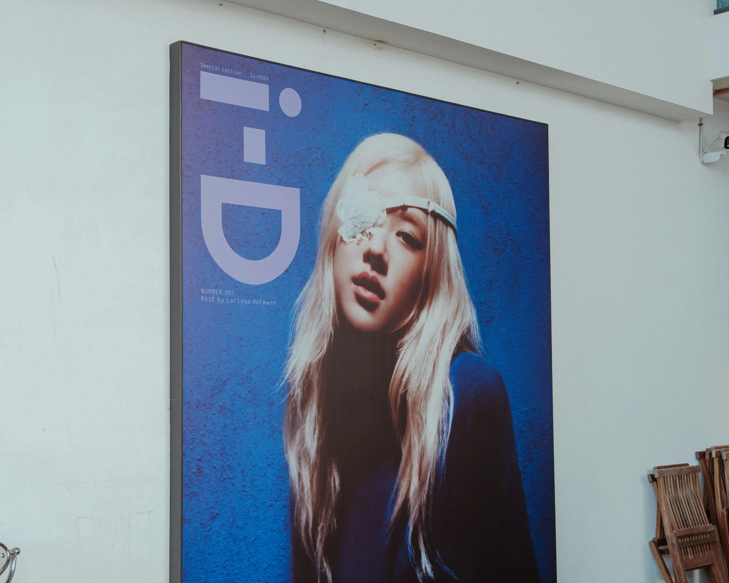 A large poster featuring a woman with platinum blonde hair washing her face with a white cloth, set against a blue textured background, with bold white letters spelling 'GU' and some smaller text at the bottom.