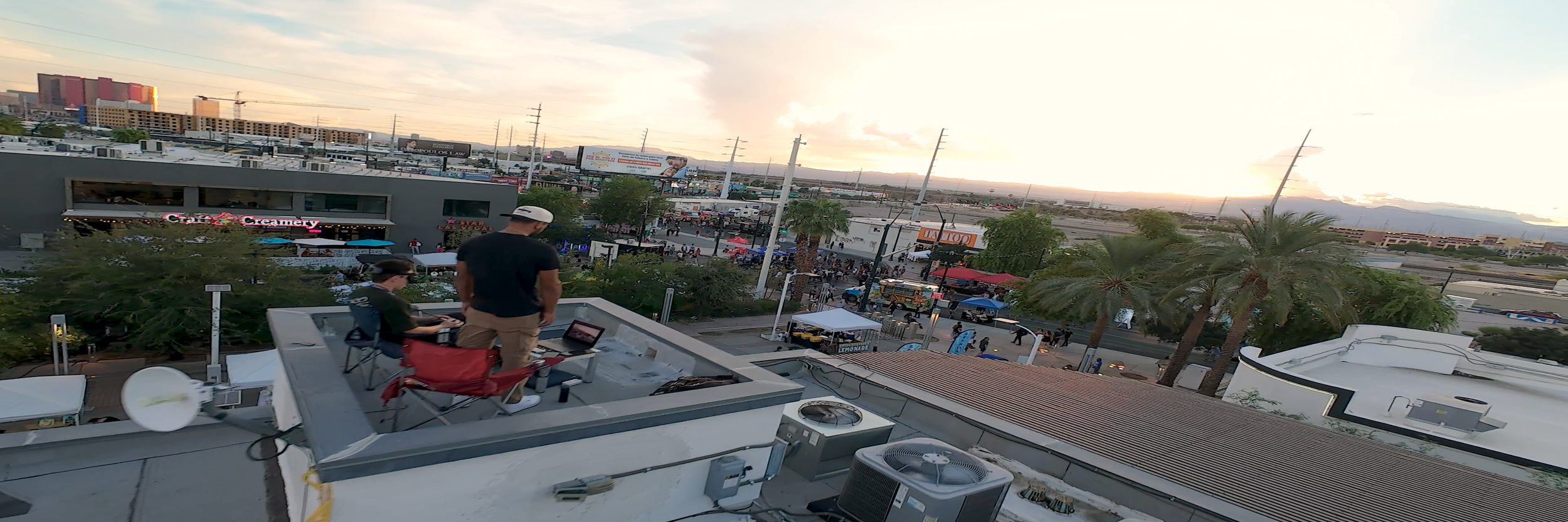 Cityscape view from a rooftop, with two people conducting FPV on operation at the Arts District for First Friday.