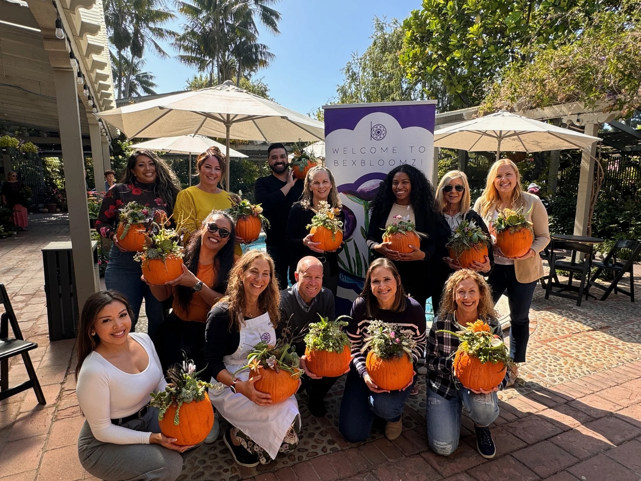 People showcasing fall arrangement with a pumpkin