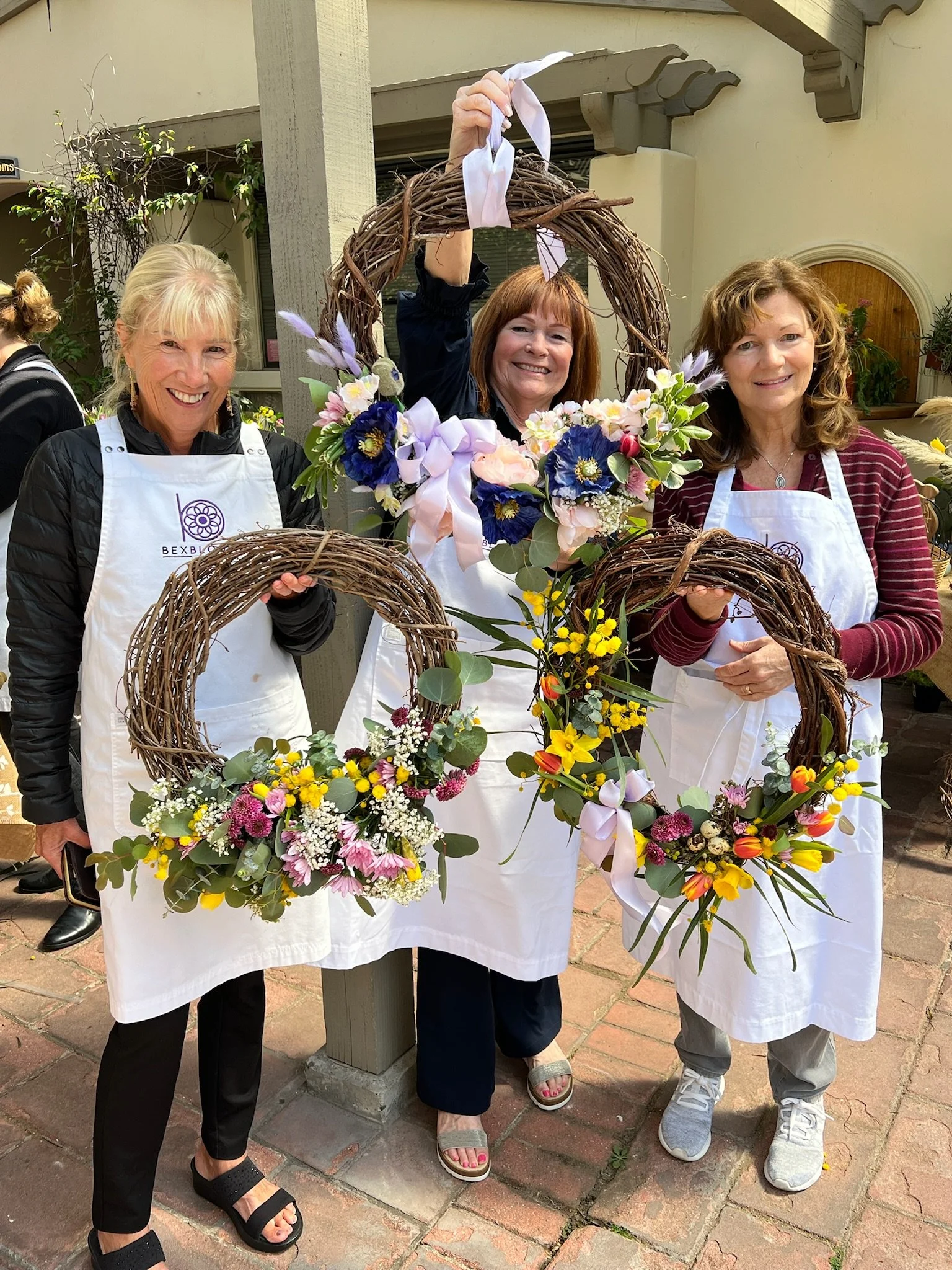 Women holding three spring wreaths