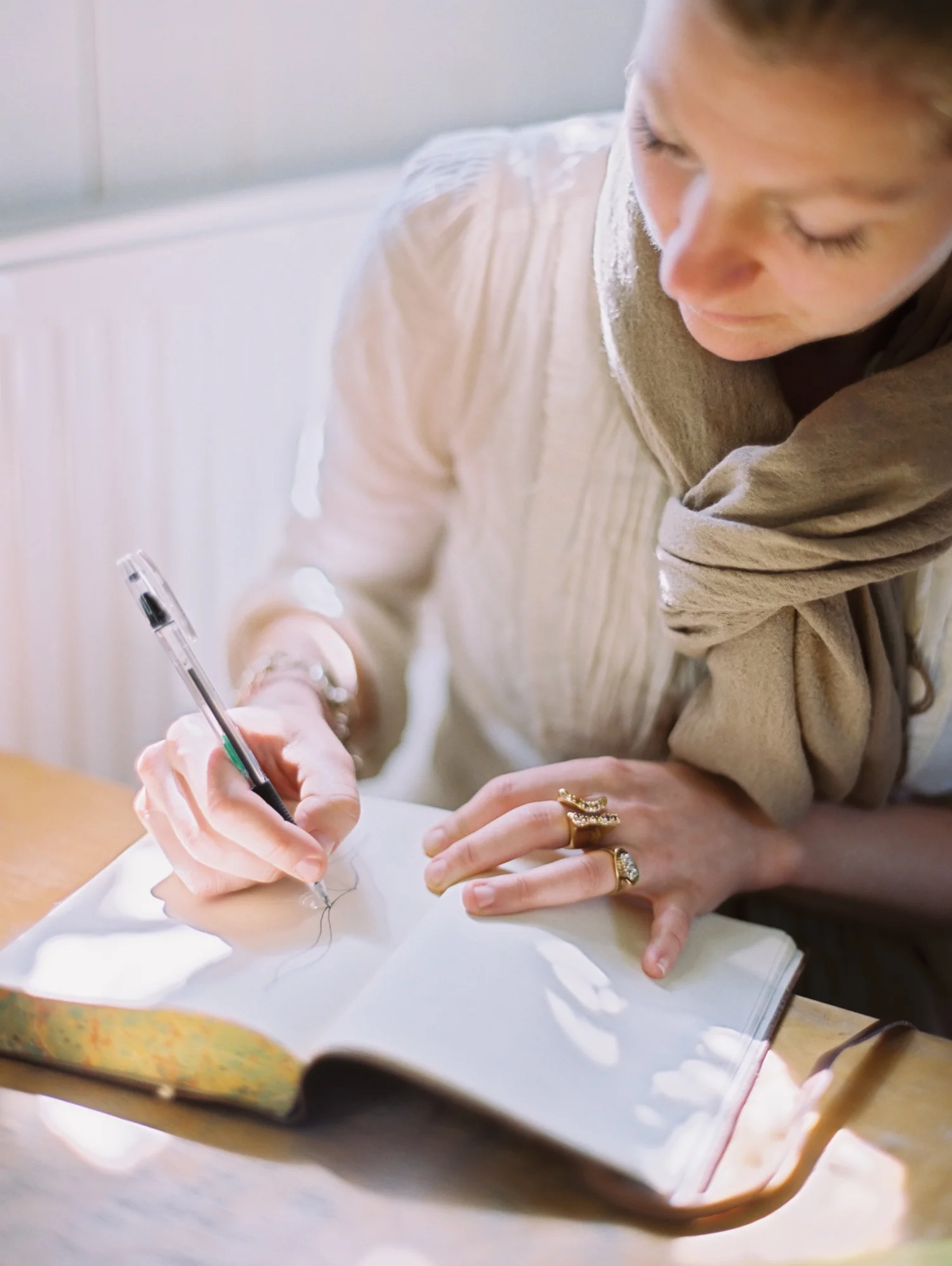 A woman writing notes in a notebook at a sunny table