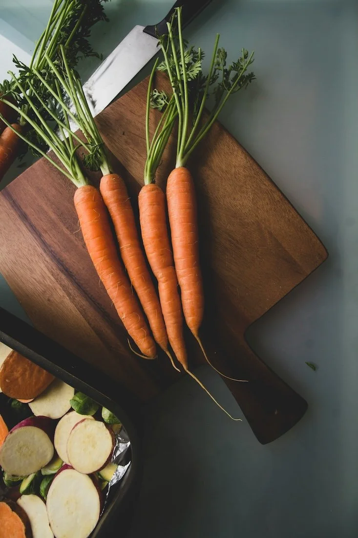 Fast forward nutrition - Fresh carrots with green tops on a wooden cutting board.