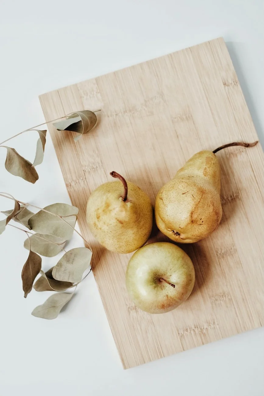 Fresh pears and halved lemons on a rustic wooden chopping board