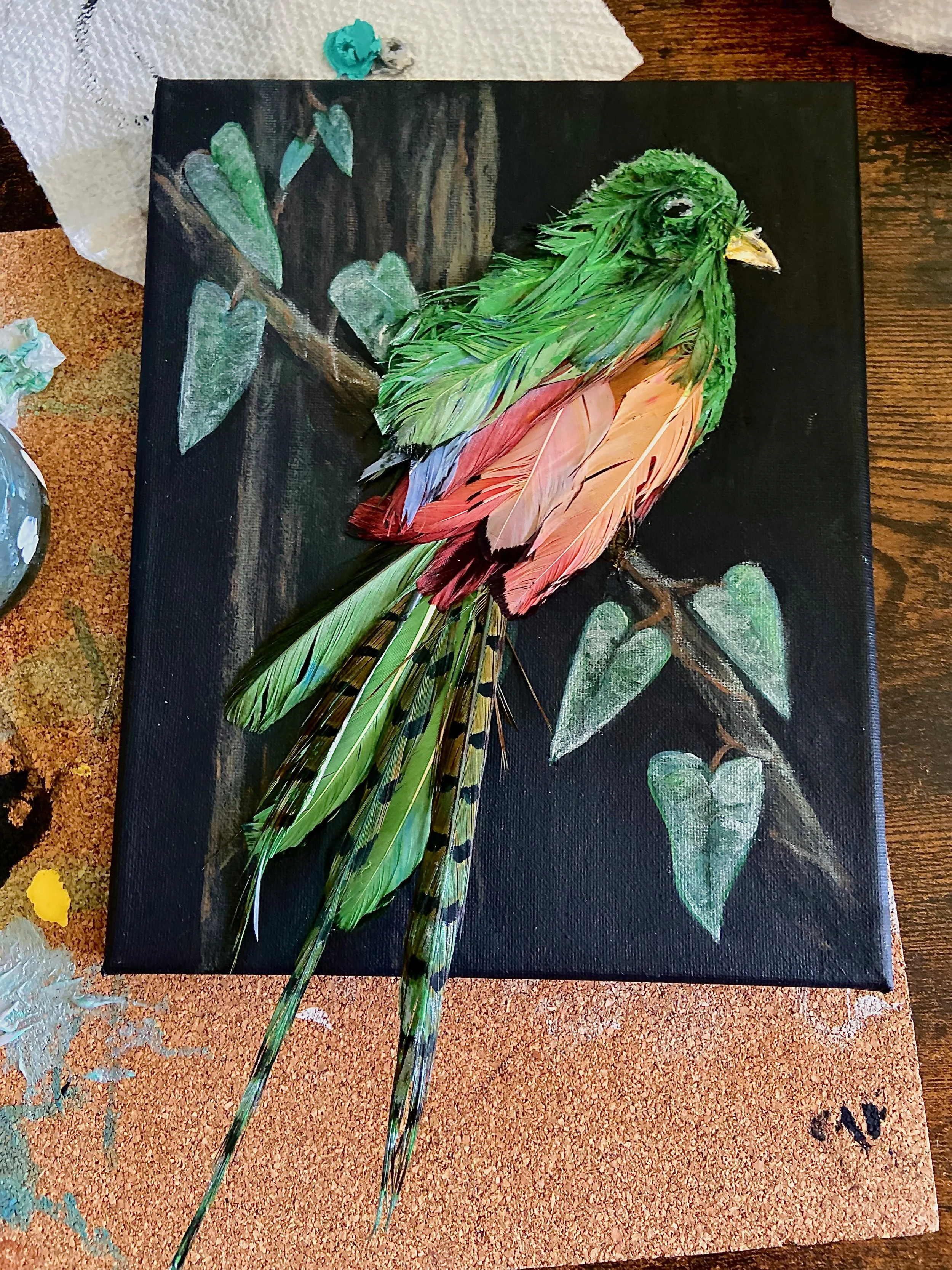 Mixed media art piece of a bird made from real feathers, perched on a branch painted on a black canvas.