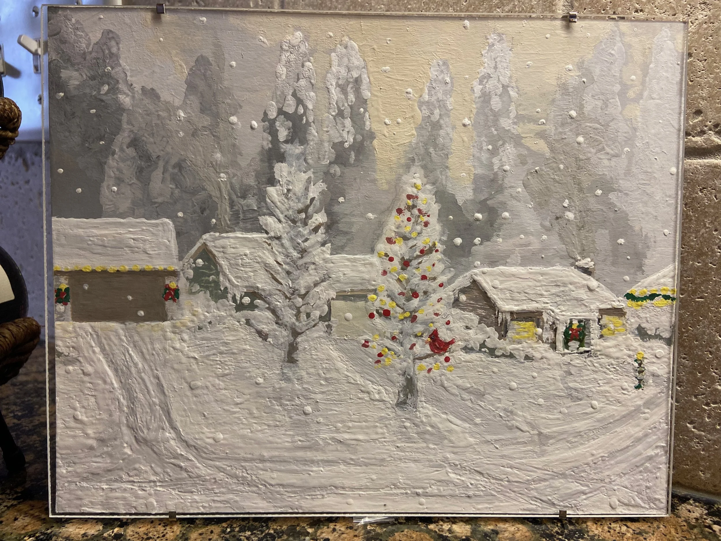 A snowy winter scene with two houses decorated for Christmas, a Christmas tree with red and yellow ornaments, and snow-covered trees and ground.