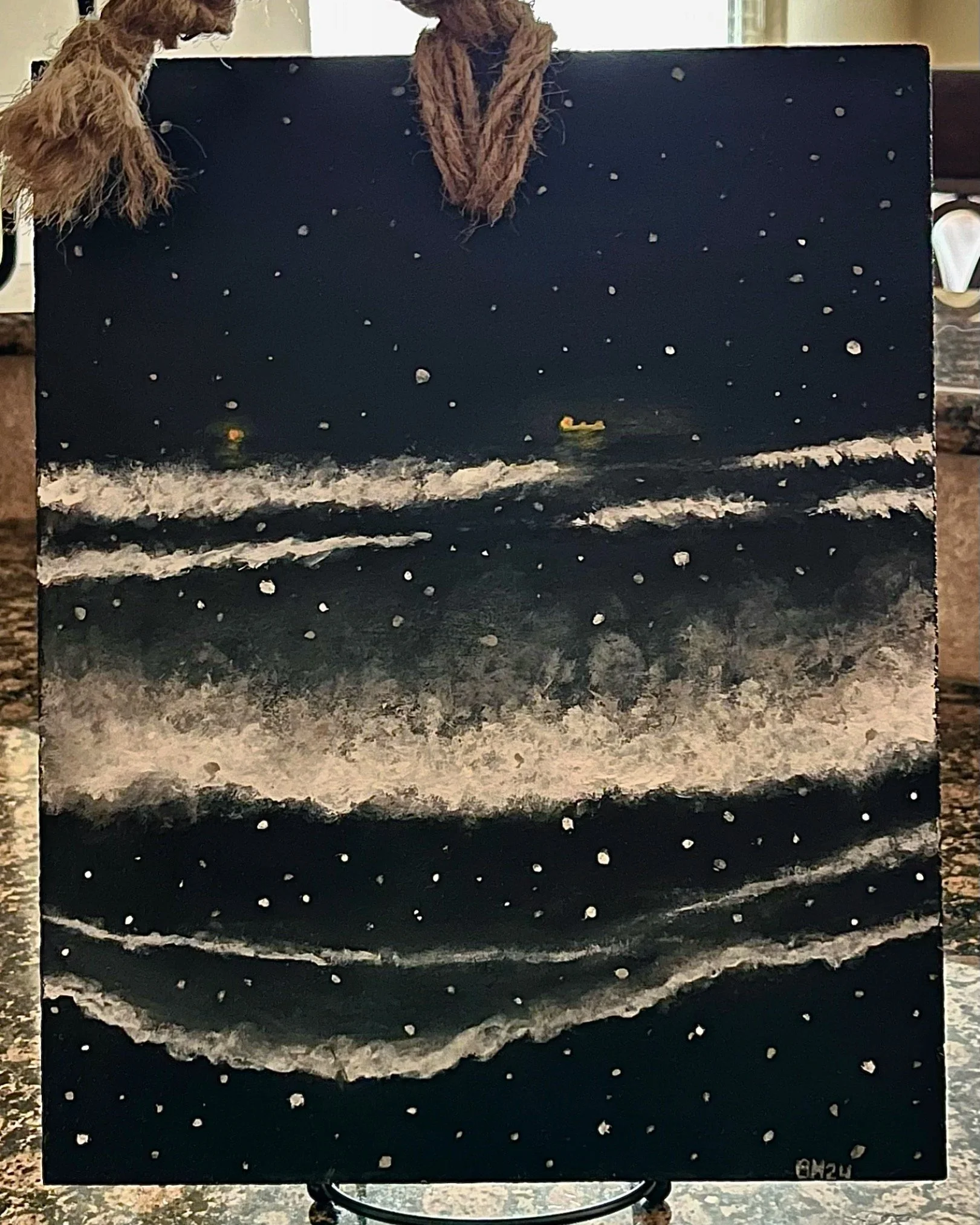 A painting of a starry night sky over the ocean with white waves crashing on the dark beach, featuring a small yellow boat in the distance.
