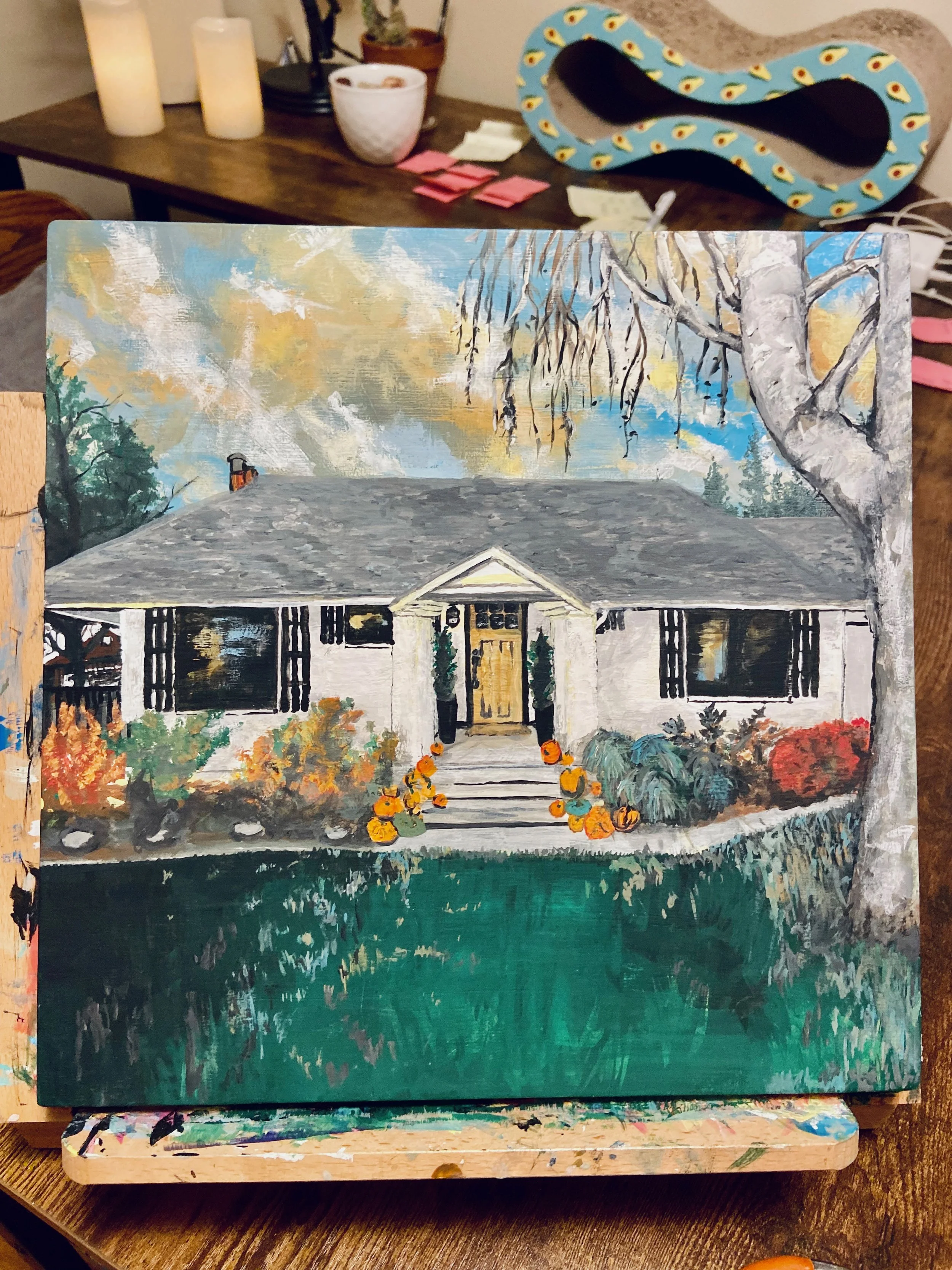 Painting of a house with a gray roof, white walls, and black shutters, surrounded by colorful bushes and trees, with fall leaves on the ground and a large tree on the right.
