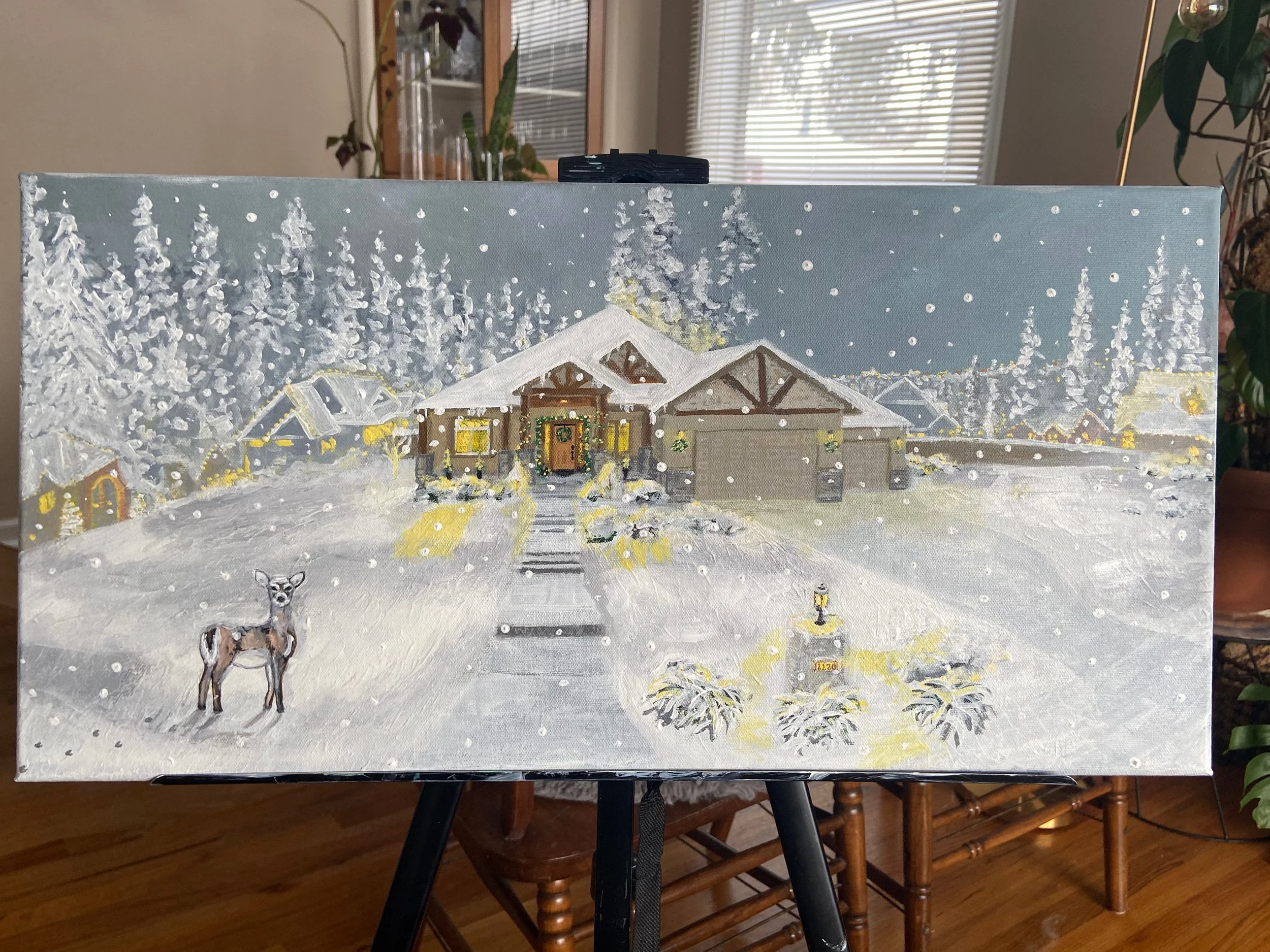 Painting of a snowy winter scene featuring a house in a forest, with a deer in the foreground, snow-covered trees, and houses in the background.