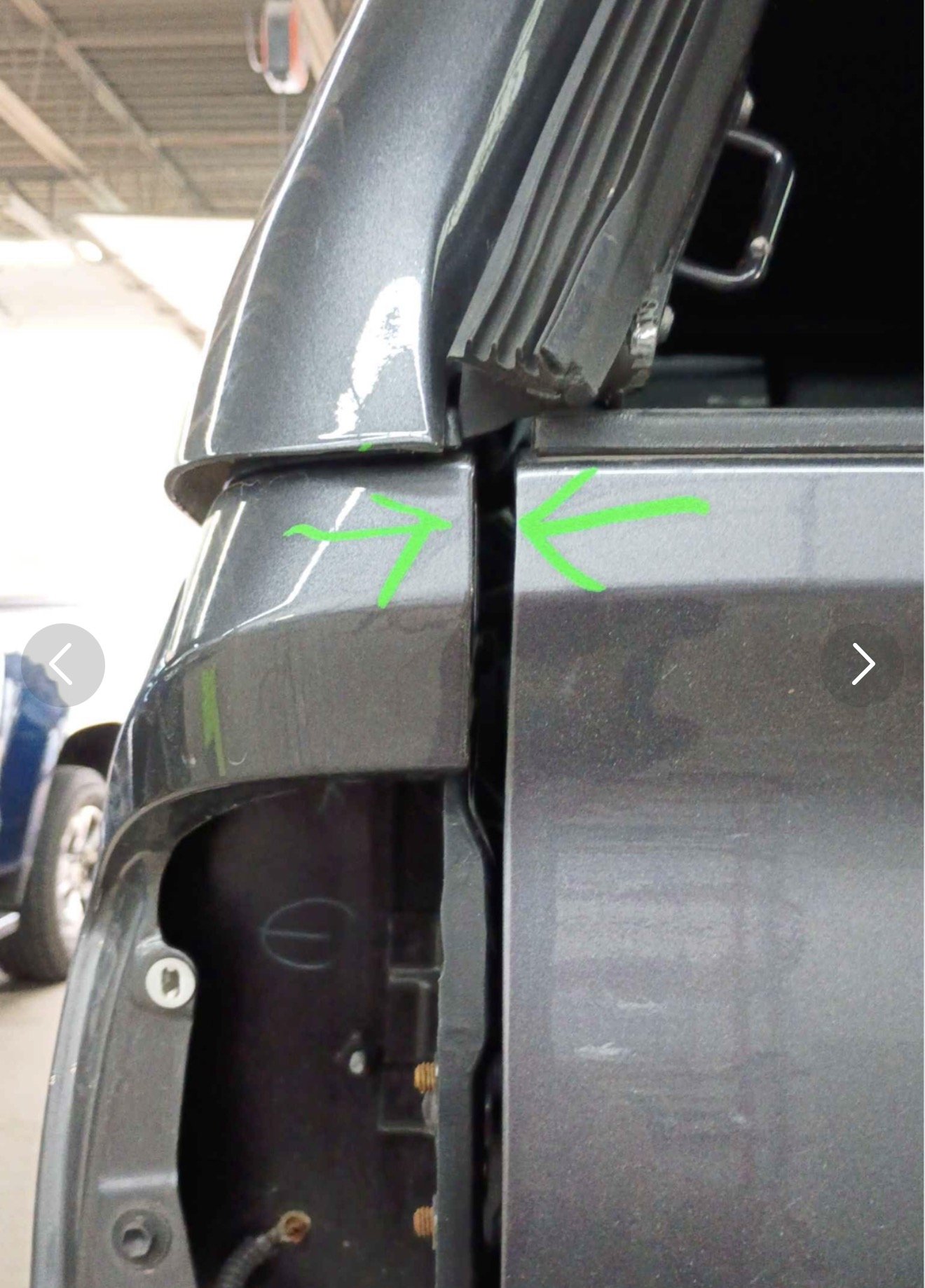 Close-up view of a damaged segment of a black electronic device, showing a crack along the edge with green markings pointing to the crack.
