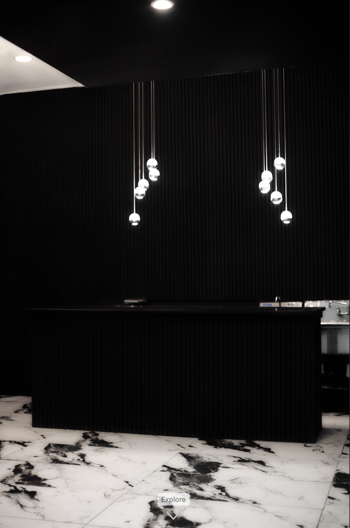 Modern black event space bar with hanging pendant lights, black textured wall, and marble flooring. Bring your own drinks and alcohol.