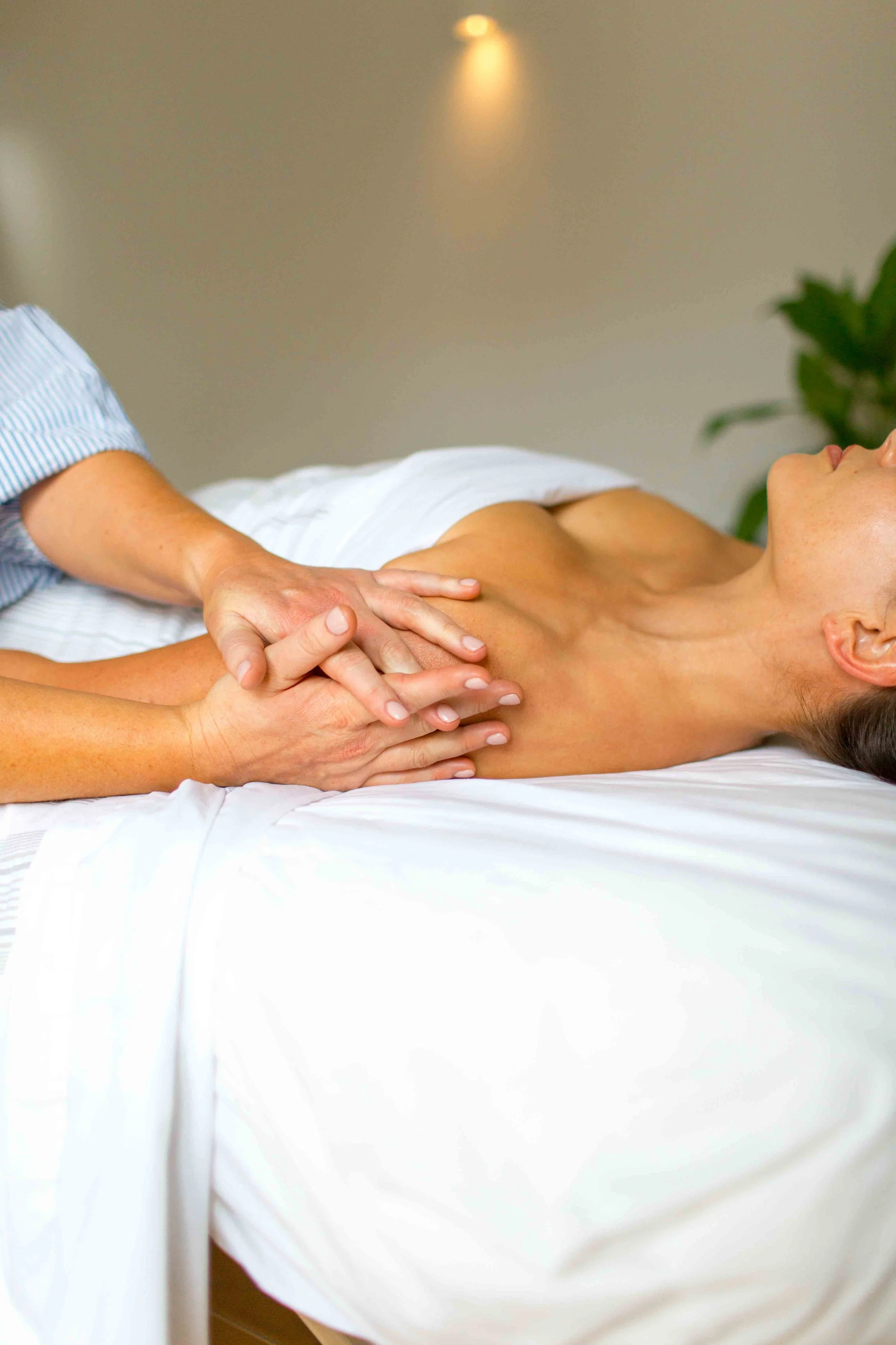 A person lying on a bed receiving a massage from a massage therapist.