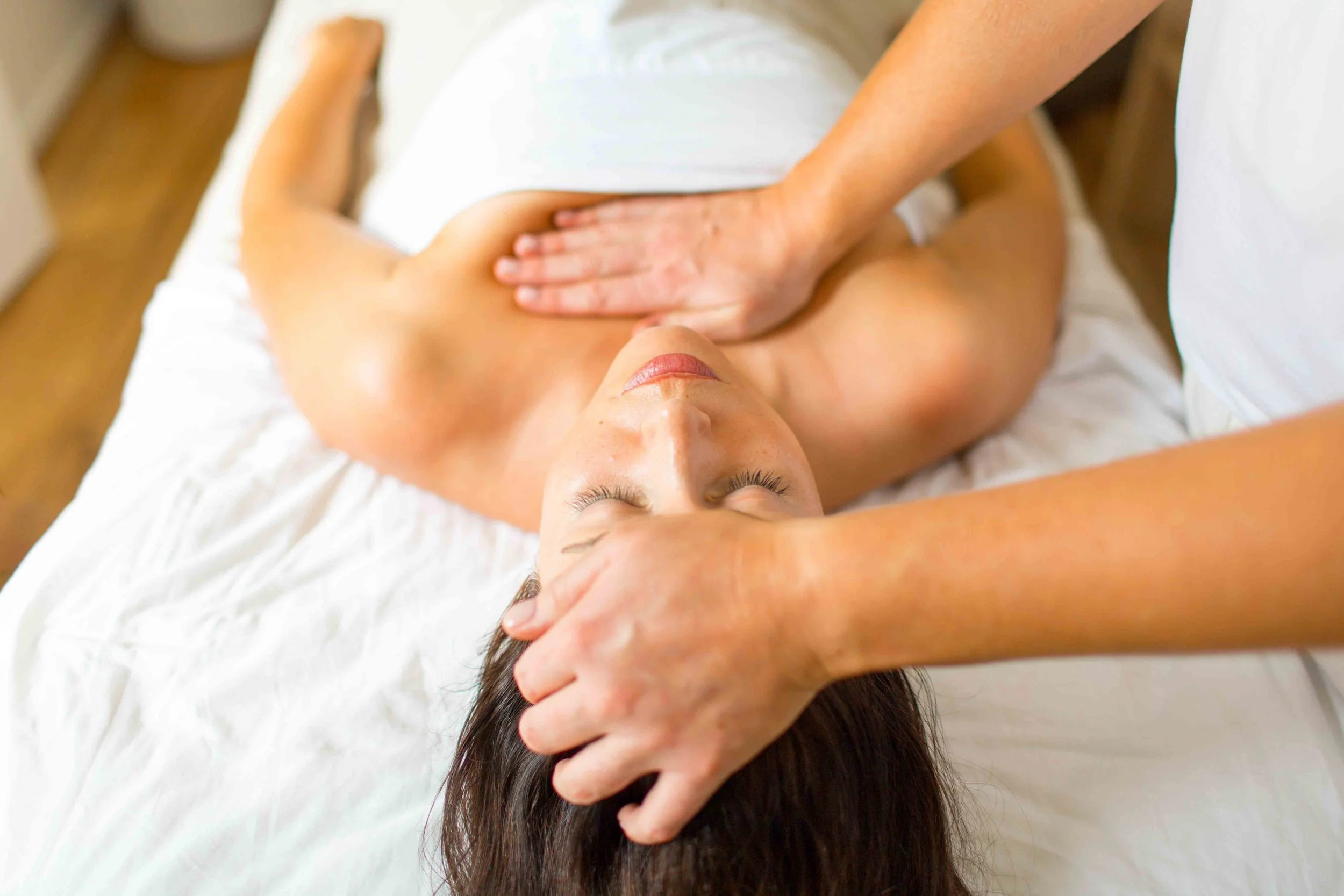 A person lying on a massage table receiving a back massage from a massage therapist.