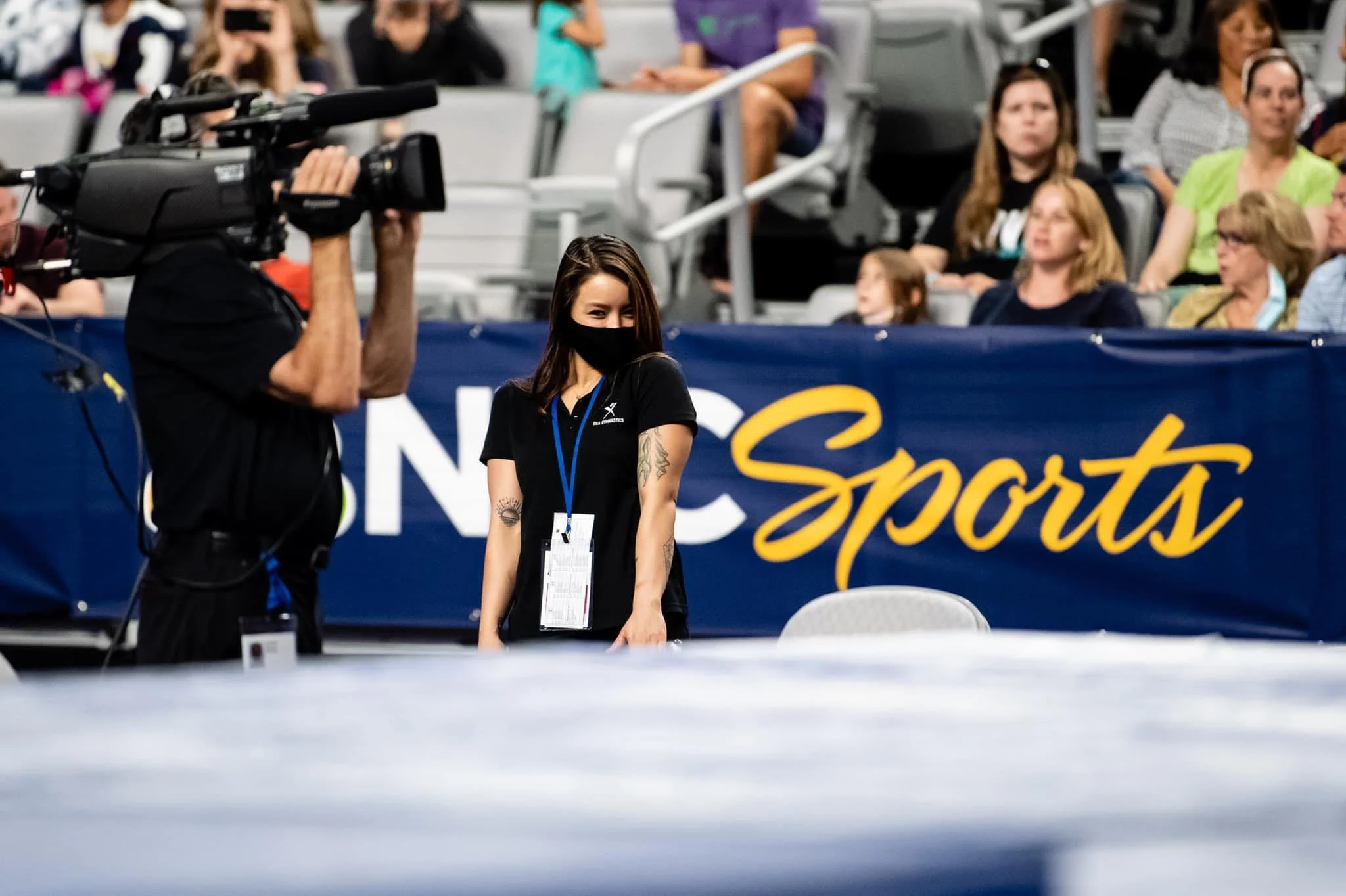 Allison Mott, professional sports photographer, smiling at the 2021 Olympic Trials near the NBC Sports logo.