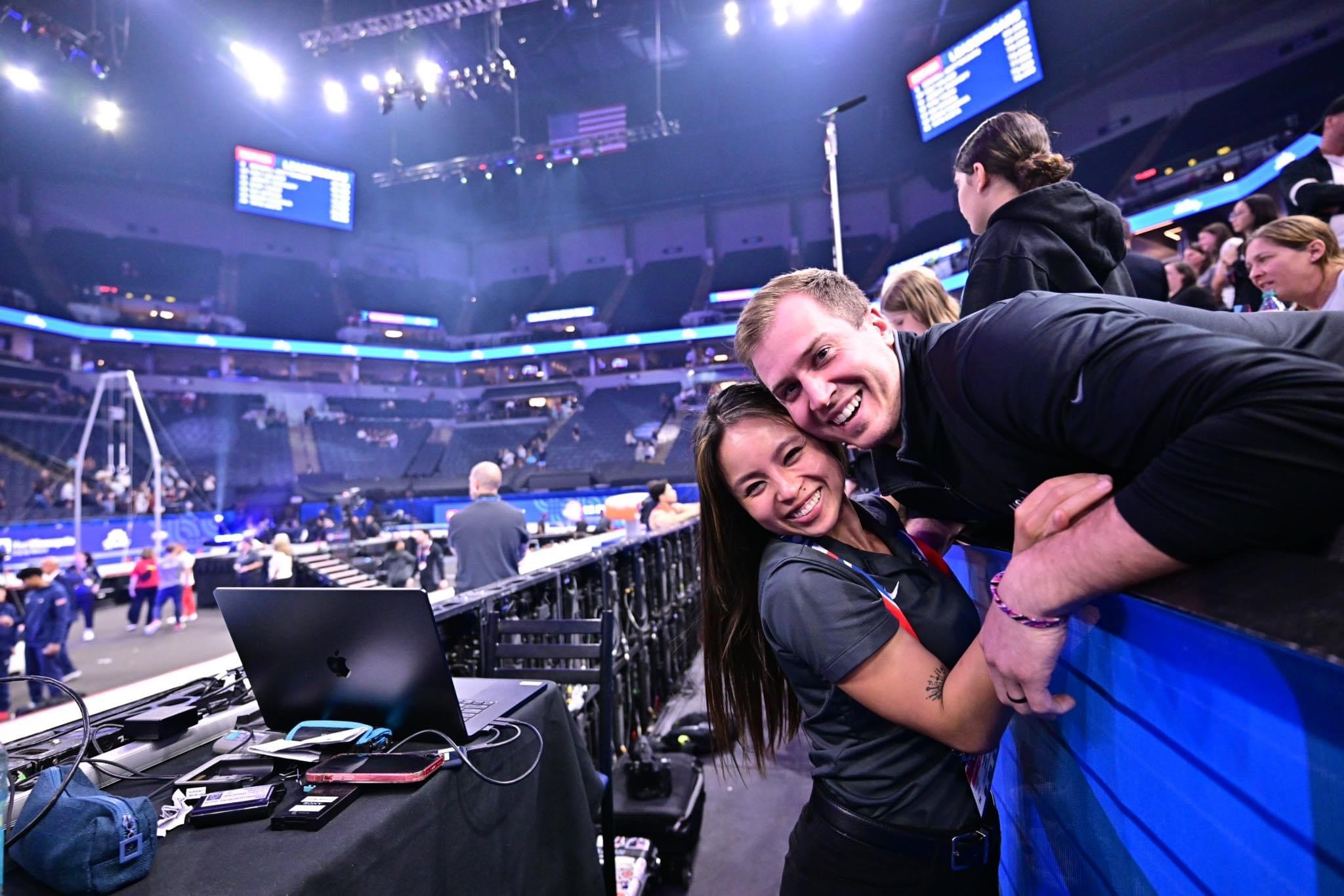 Professional gymnastics photographer Allison Mott sharing a hug with her husband on the field of play at the 2024 US Olympic Gymnastics Trials at the Target Center in Minneapolis.