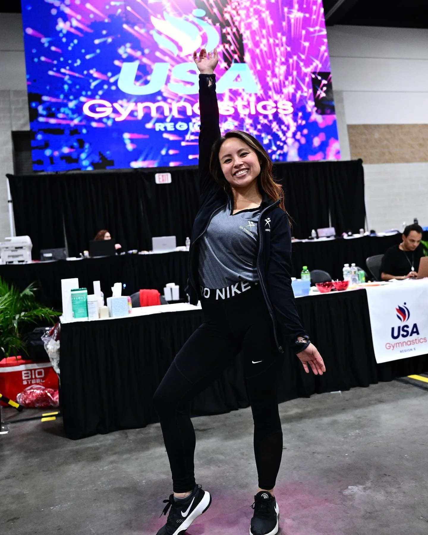 Allison Mott (formerly Allison Cheng) smiling at the USA Gymnastics Region 6 Championships. A documentary wedding and sports photographer with 10+ years of experience, Allison is pictured on the competition floor in a moment of calm amidst the high-s